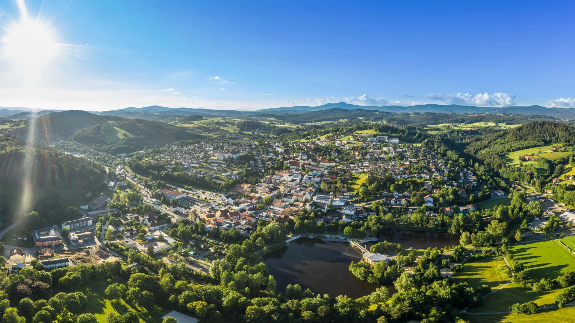 Luftaufnahme einer Drohne der Stadt Grafenau im bayerischen Wald mit Berg Arber Rachel Lusen im Sommer mit Sonne und Sonnenstrahlen, Deutschland