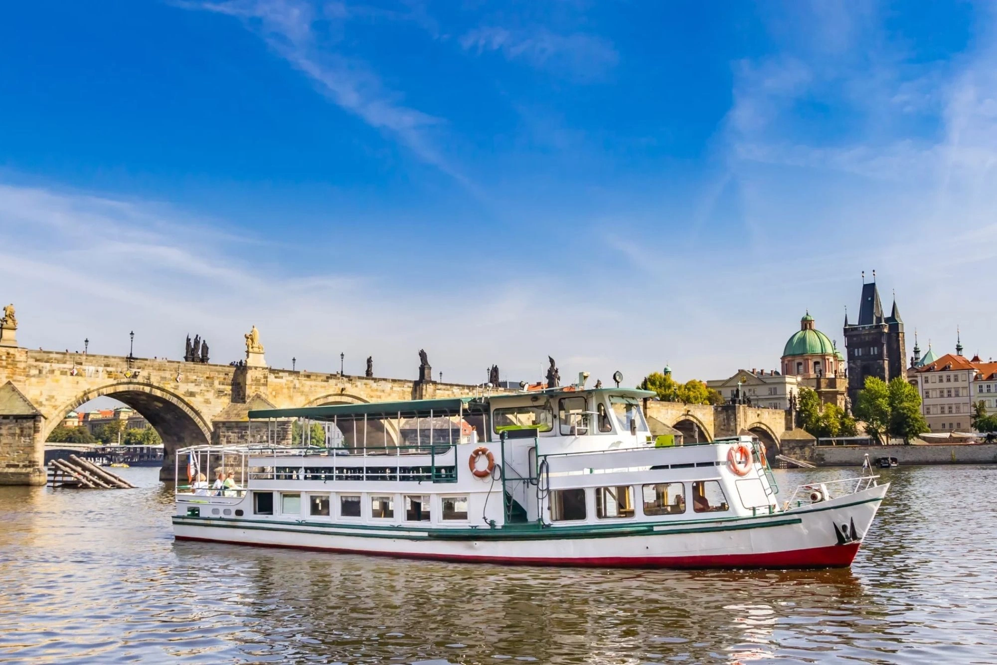 Ein Flussboot auf der Moldau mit der Karlsbrücke im Hintergrund.