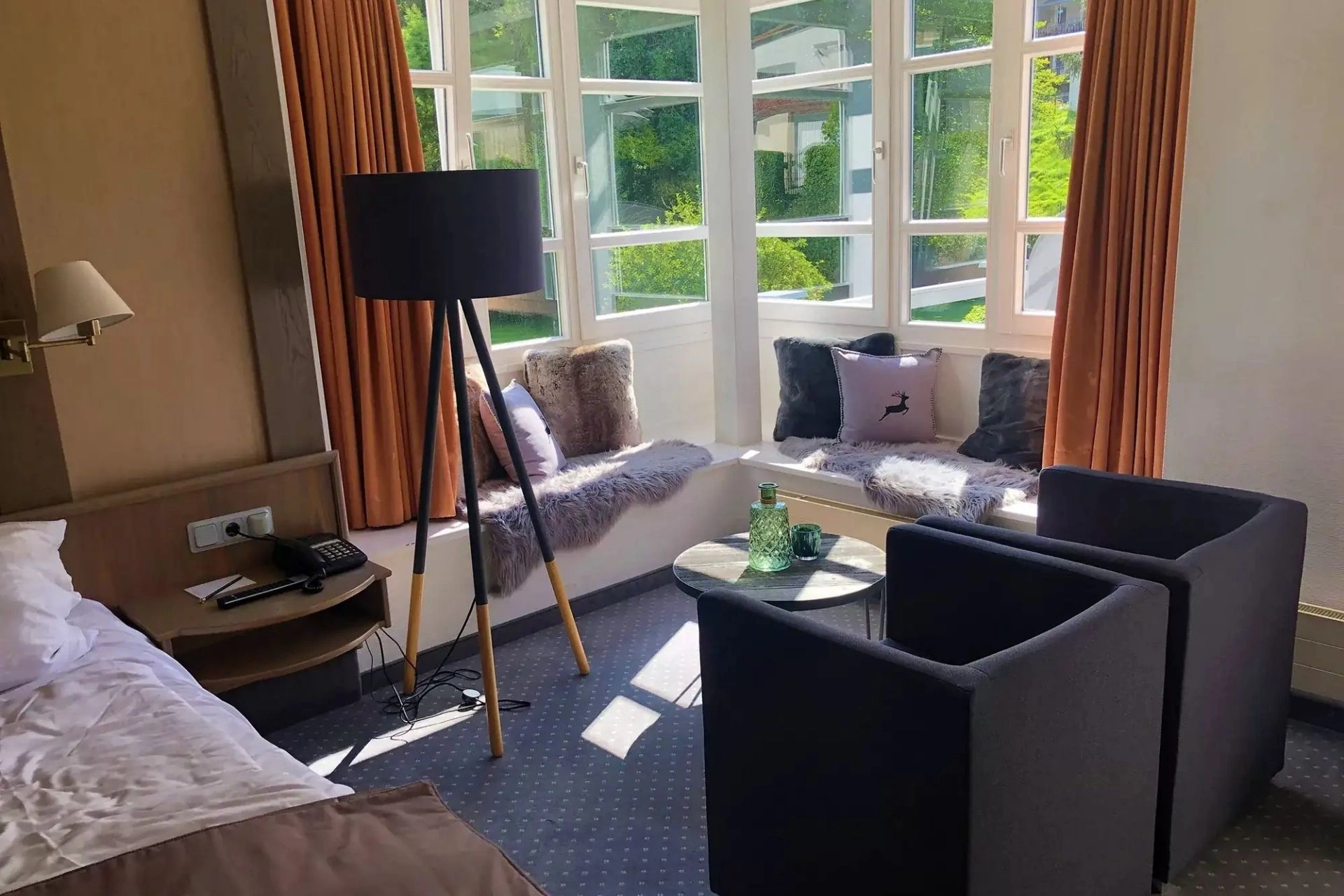Schlafbereich mit Doppelbett und gemütlicher Sitzecke mit Blick ins Grüne im Mauerschlößchenzimmer im Romantisches Hotel Menzhausen