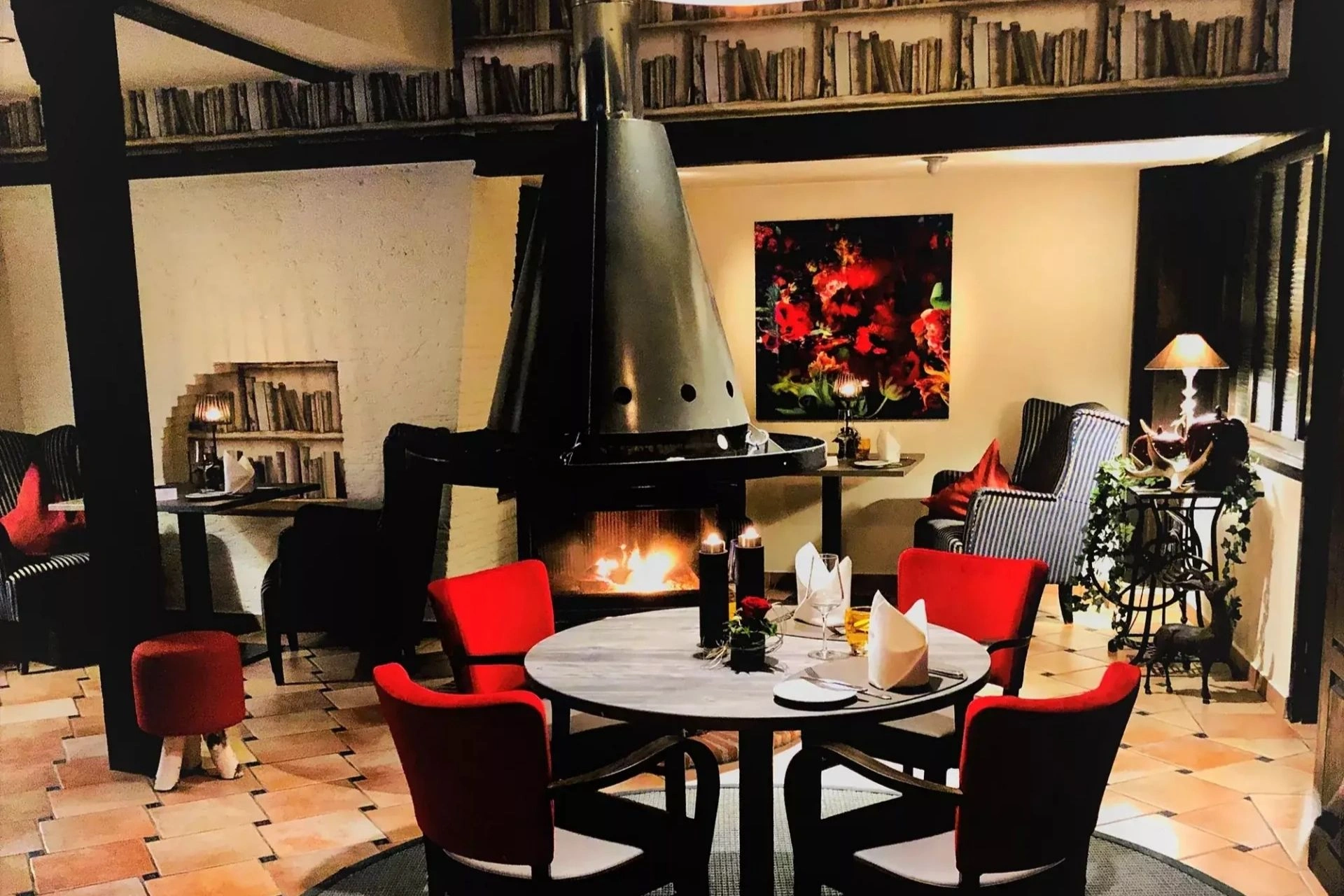 Gemütliches Kaminzimmer mit Tisch zum Abendessen und Ohrensessel im Romantischen Hotel Menzhausen