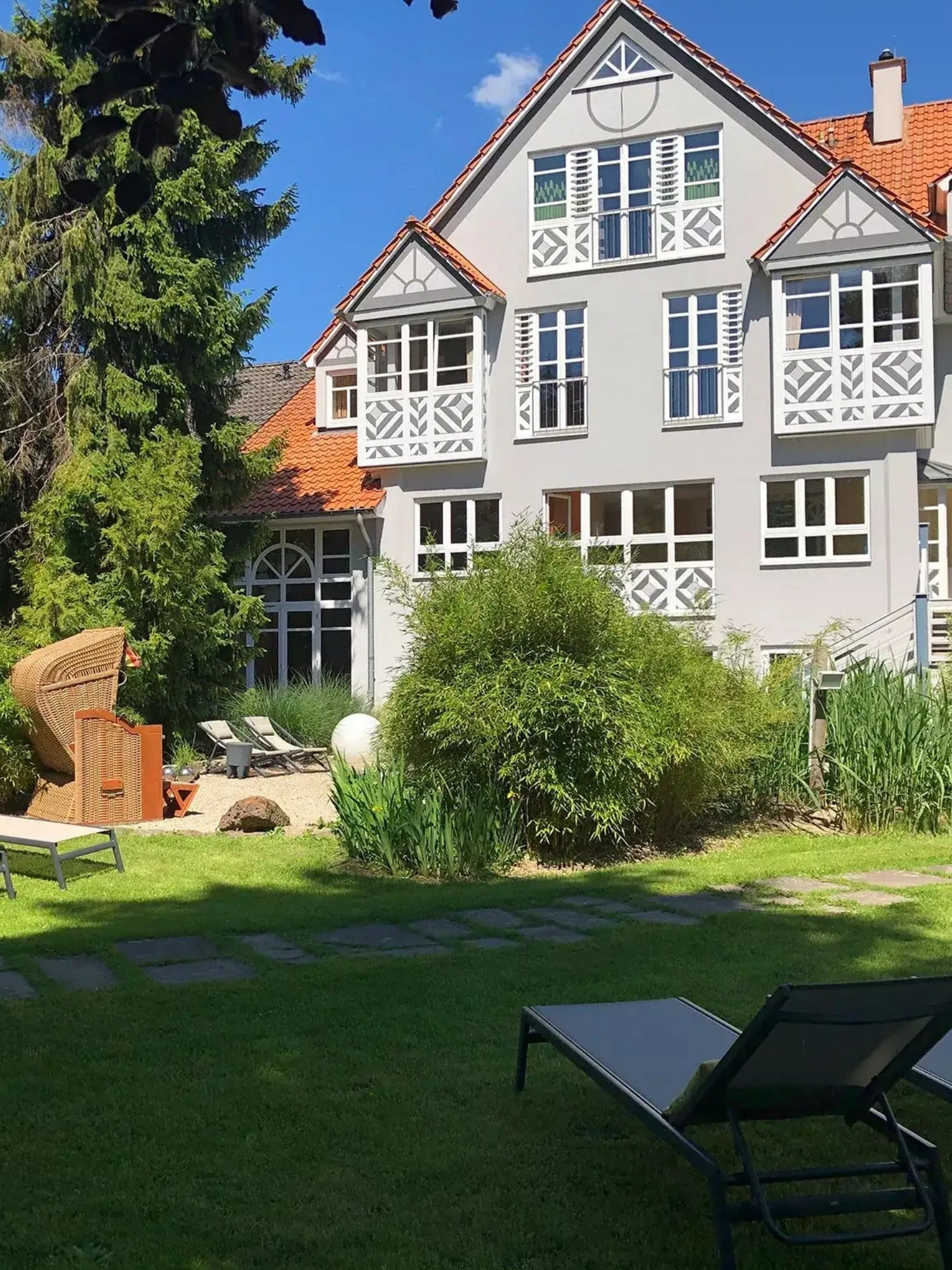 Garten mit Liegen und Strandkorb und Blick auf die Außenansicht vom Romantisches Hotel Menzhausen