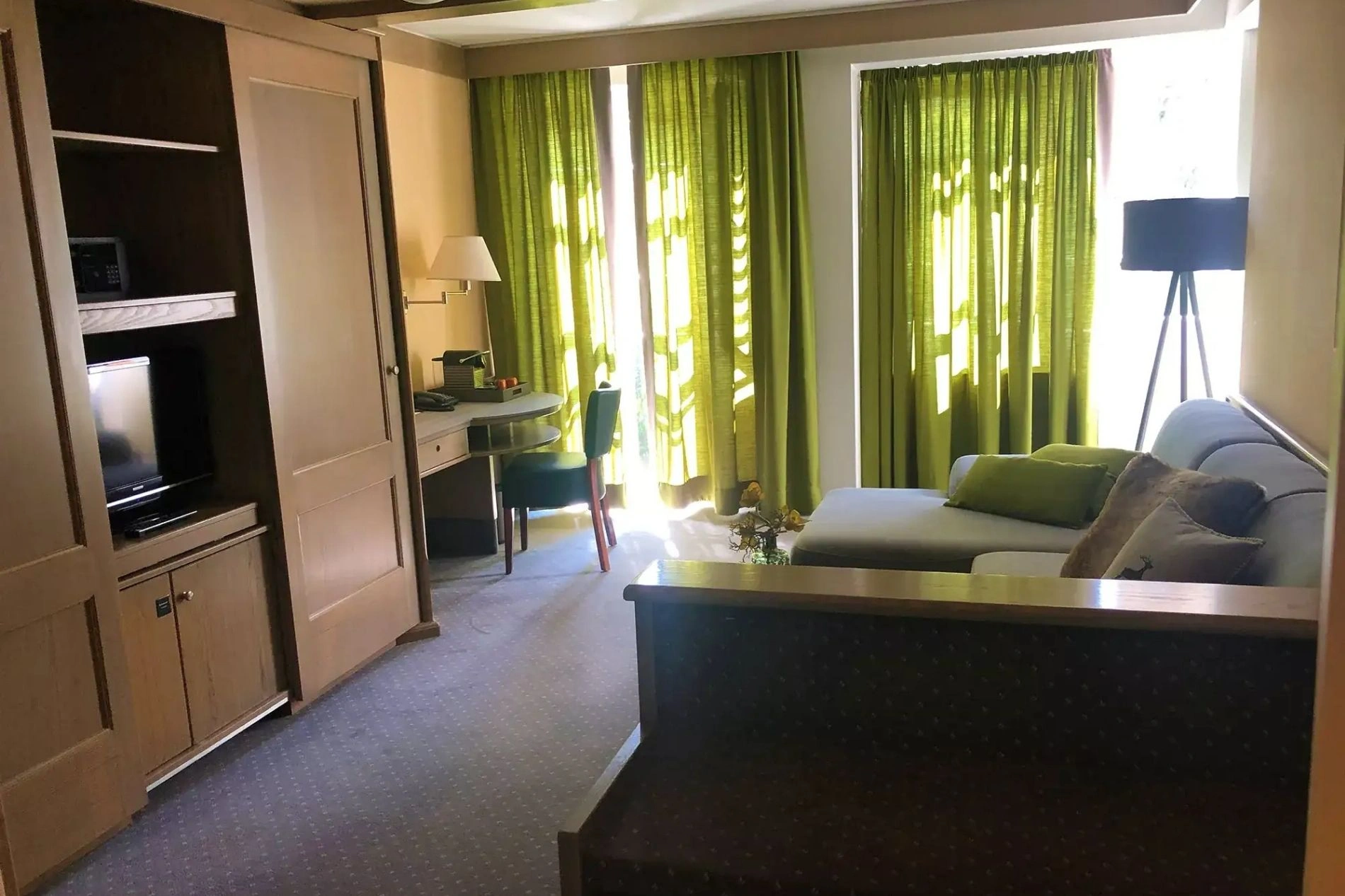 Der Wohnbereich mit Sofa, Schreibtisch und Fernseher im Mauerschlößchenzimmer im Romantisches Hotel Menzhausen