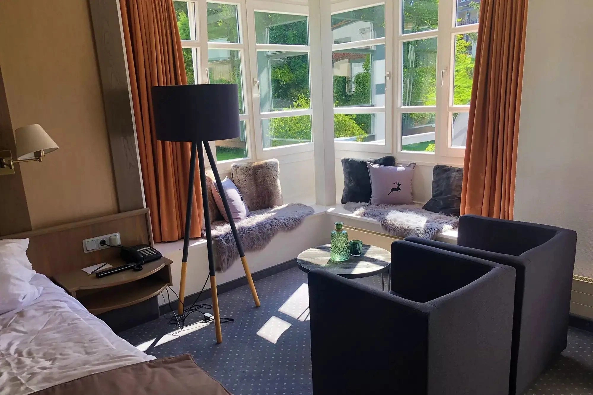 Schlafbereich mit Doppelbett und gemütlicher Sitzecke mit Blick ins Grüne im Mauerschlößchenzimmer im Romantisches Hotel Menzhausen