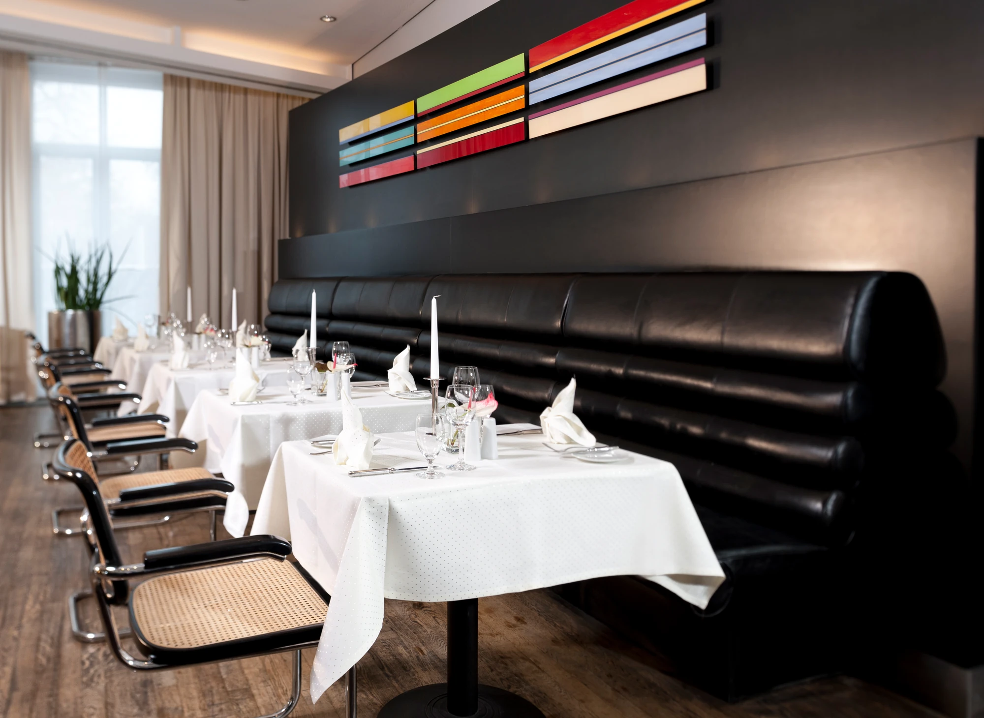 Dorint Hotel Potsdam, Tische im Restaurant mit schwarz-gepolsterter Sitzbank