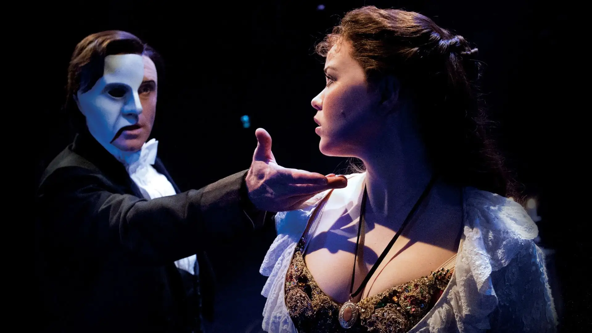 Zwei Schauspieler in Bühnenkostümen des Musicals Phantom der Oper, der Mann mit ausgestrecktem Arm, die Frau mit langem Haar und Spitzenkleid