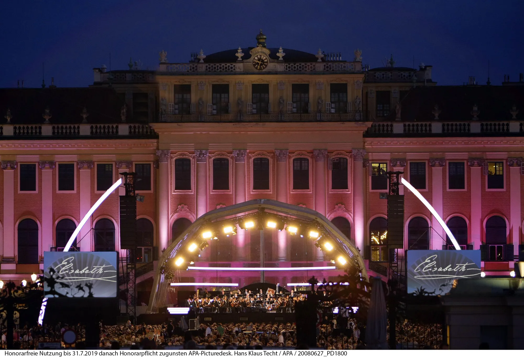 Elisabeth Konzertaufführung - Konzert unter dunklem Himmel, majestätisches Schloss Schönbrunn pink beleuchtet im Hintergrund