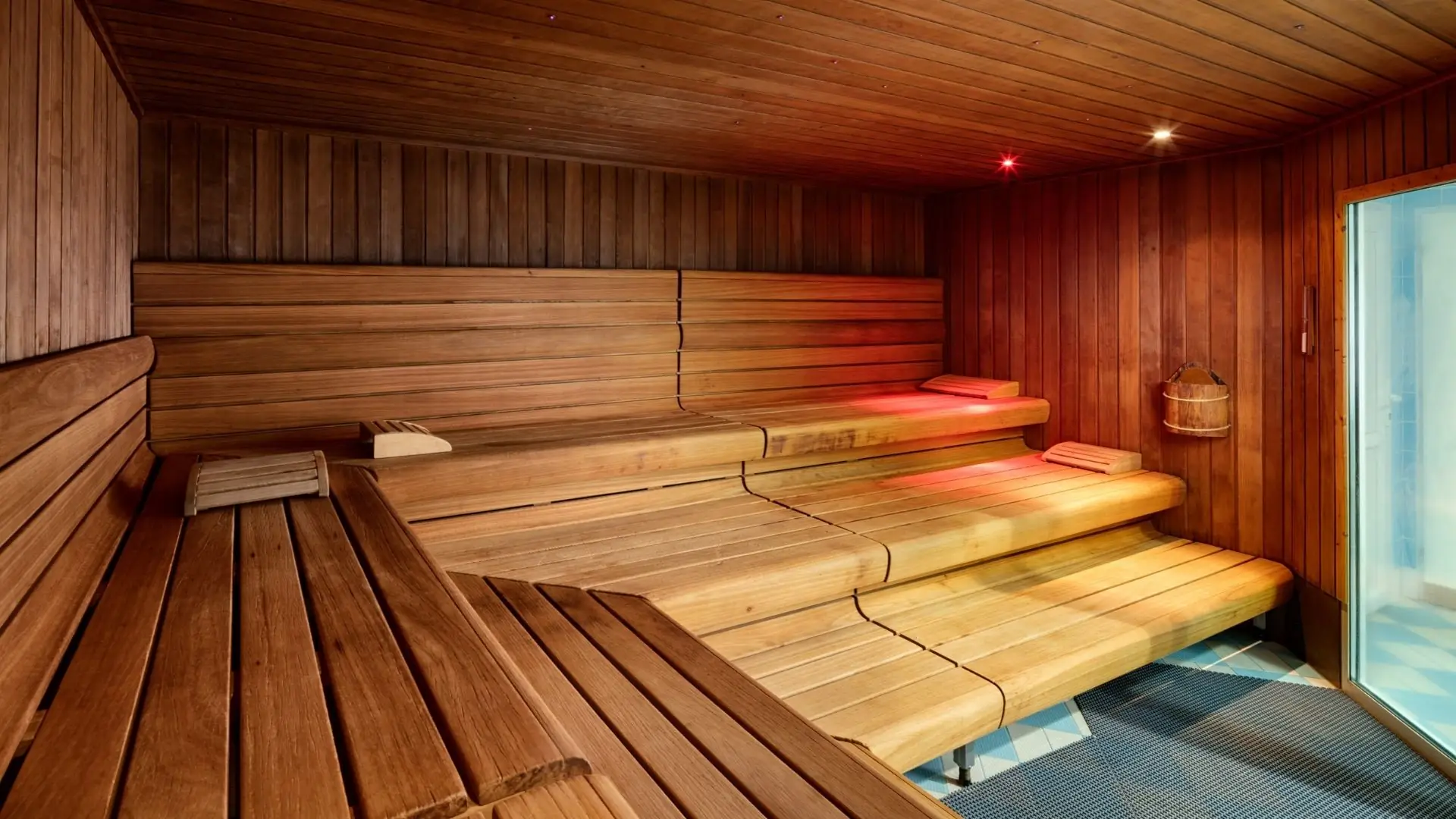 Saunaraum mit mehrstufigen Holzbänken und Holzwänden, rechteckiges Fenster mit Blick nach außen.