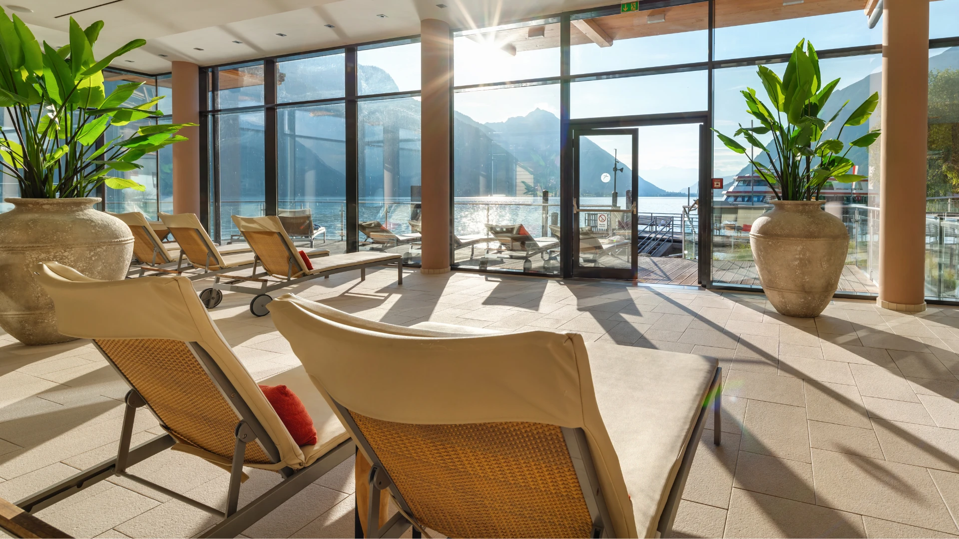 Die lichtdurchflutete Wellness-Lounge des aja Fürstenhaus am Achensee bietet stilvolle Liegen mit Panoramablick auf den Achensee und die umliegenden Berge – ideal zum Entspannen und Genießen der Natur.