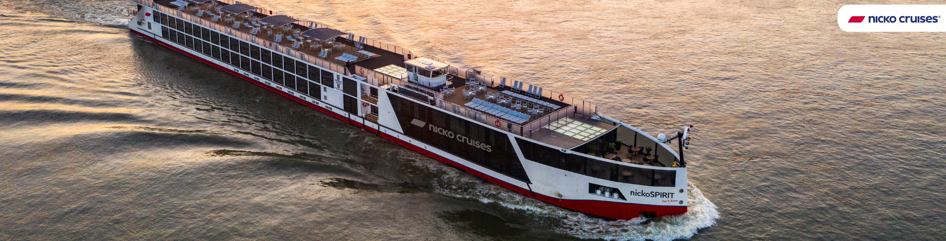 Flusskreuzfahrtschiff mit dem Schriftzug 'nicko cruises' fährt auf einem Fluss