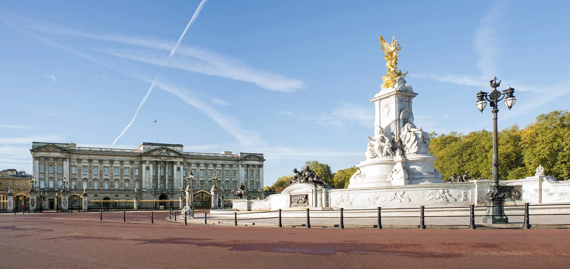 Buckingham Palace ist die offizielle Residenz der britischen Monarchie in London. Die beeindruckende Fassade des Palastes ist im neoklassizistischen Stil gestaltet und von einem großzügigen Platz umgeben. Im Vordergrund steht das Victoria Memorial, das zu Ehren von Königin Victoria errichtet wurde. Es zeigt kunstvolle Statuen und wird von prächtigen, geschmückten Zäunen und Laternen flankiert. Bei klarem Himmel ist die Architektur des Palastes besonders gut sichtbar und zieht Touristen aus aller Welt an, die die Wachablösung und andere Zeremonien beobachten möchten.
