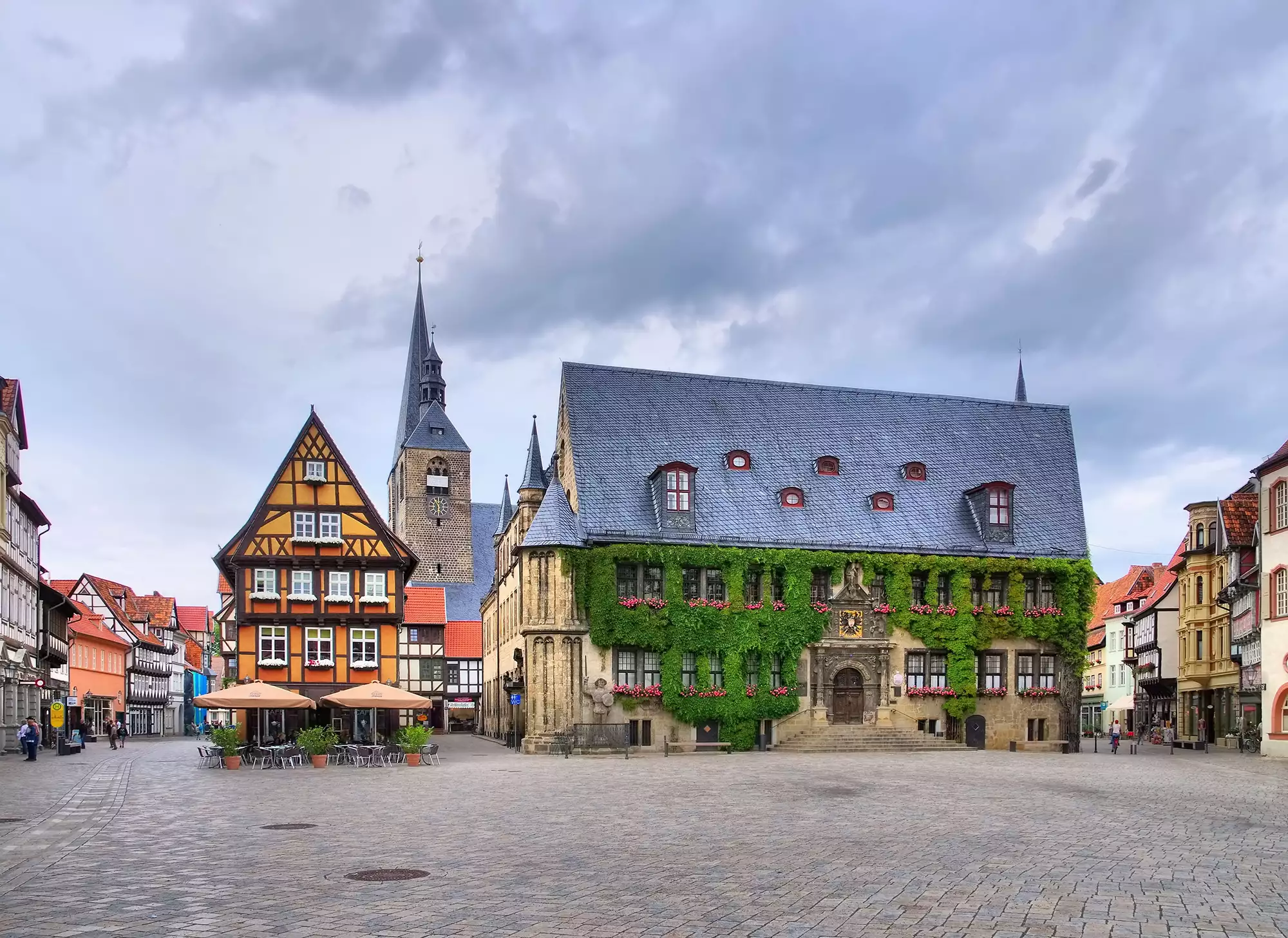 Blick vom Marktplatz auf die Marktkirche zwischen dem Rathaus und einem gelben Fachwerkhaus mit Spitzdach in Quedlinburg