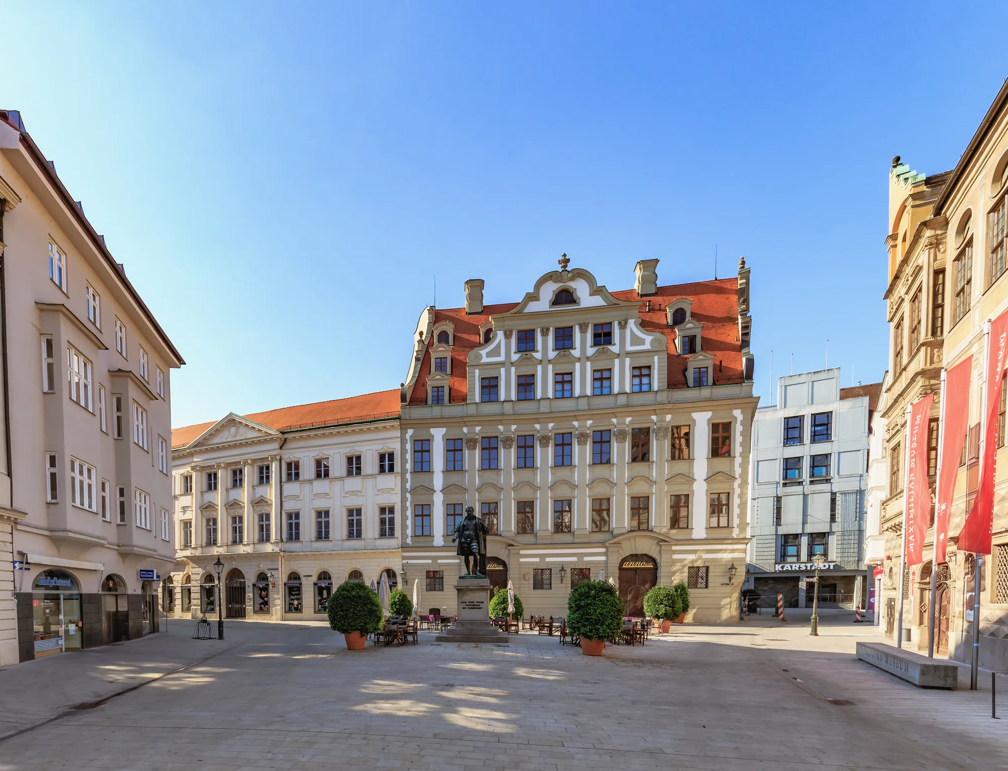 Blick auf das denkmalgeschütze Köpfhaus mit dem Fuggerdenkmal und strahlendblauen Himmel in Augsburg