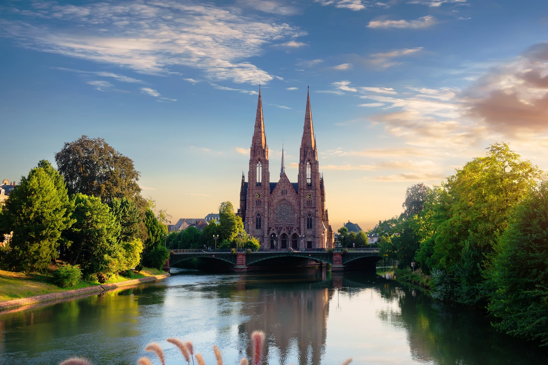 Landschaftsaufnahme einer Kirche im Sonnenuntergang mit ruhigem Wasser.
