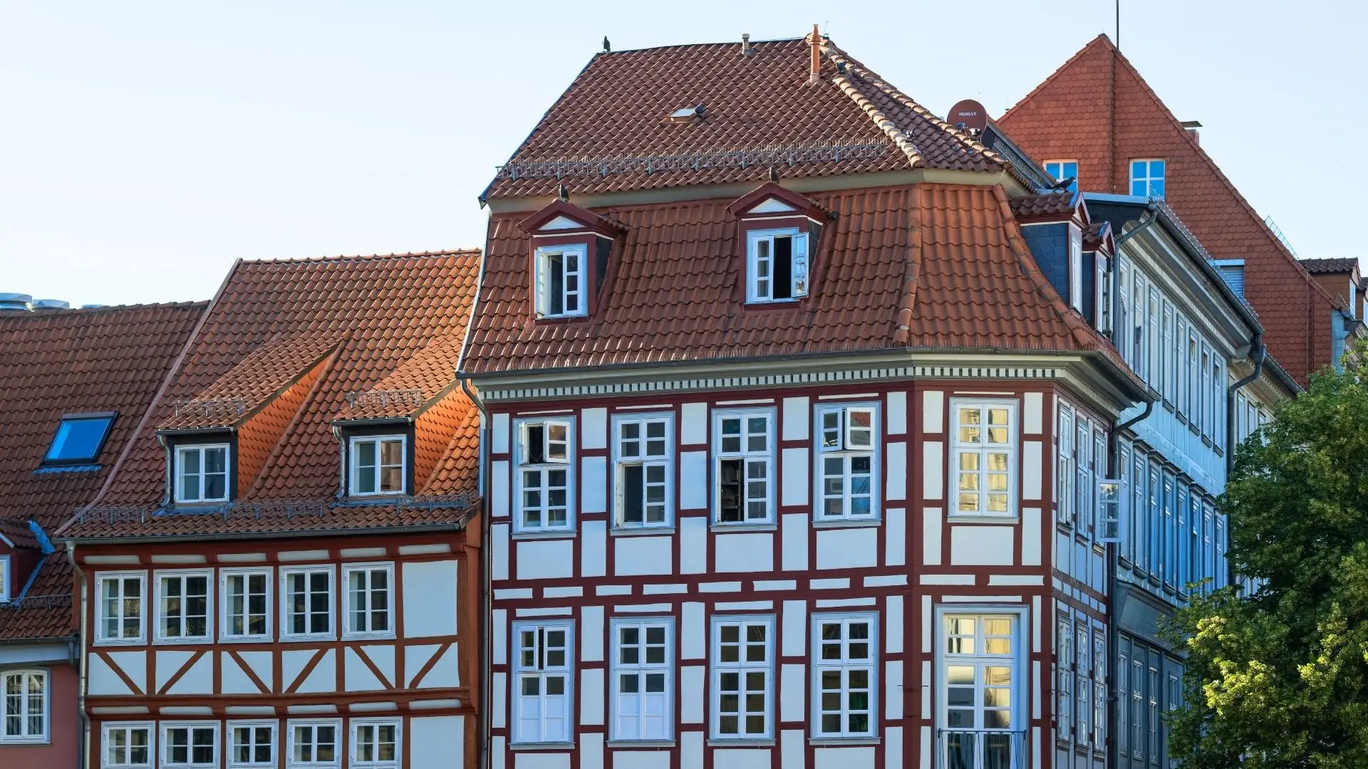 Fachwerkhaus in Göttingen mit roten Ziegeldächern, weißen Wänden und roten Balken. Fenster mit weißen Rahmen und Sprossen.