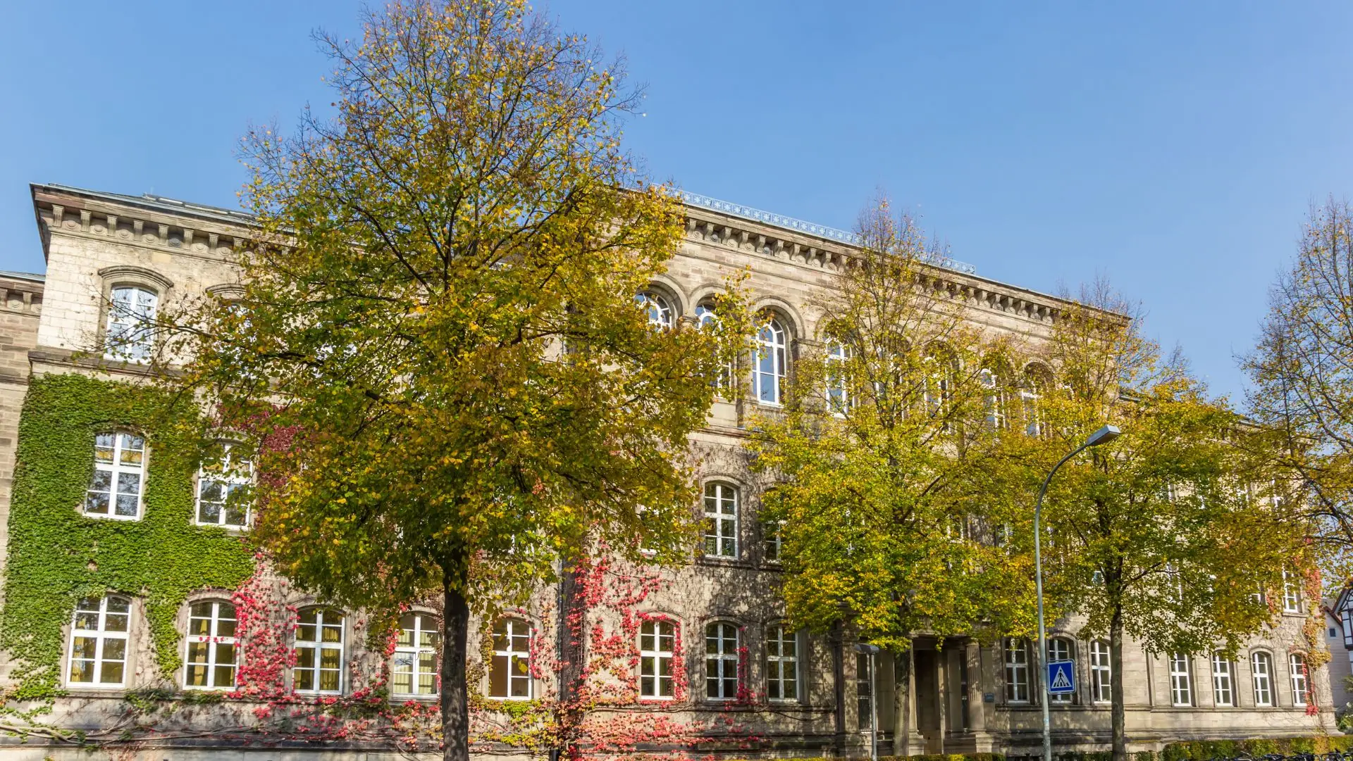 Historisches Schulgebäude in Göttingen mit mehreren Fenstern und Bäumen im Vordergrund im Herbst