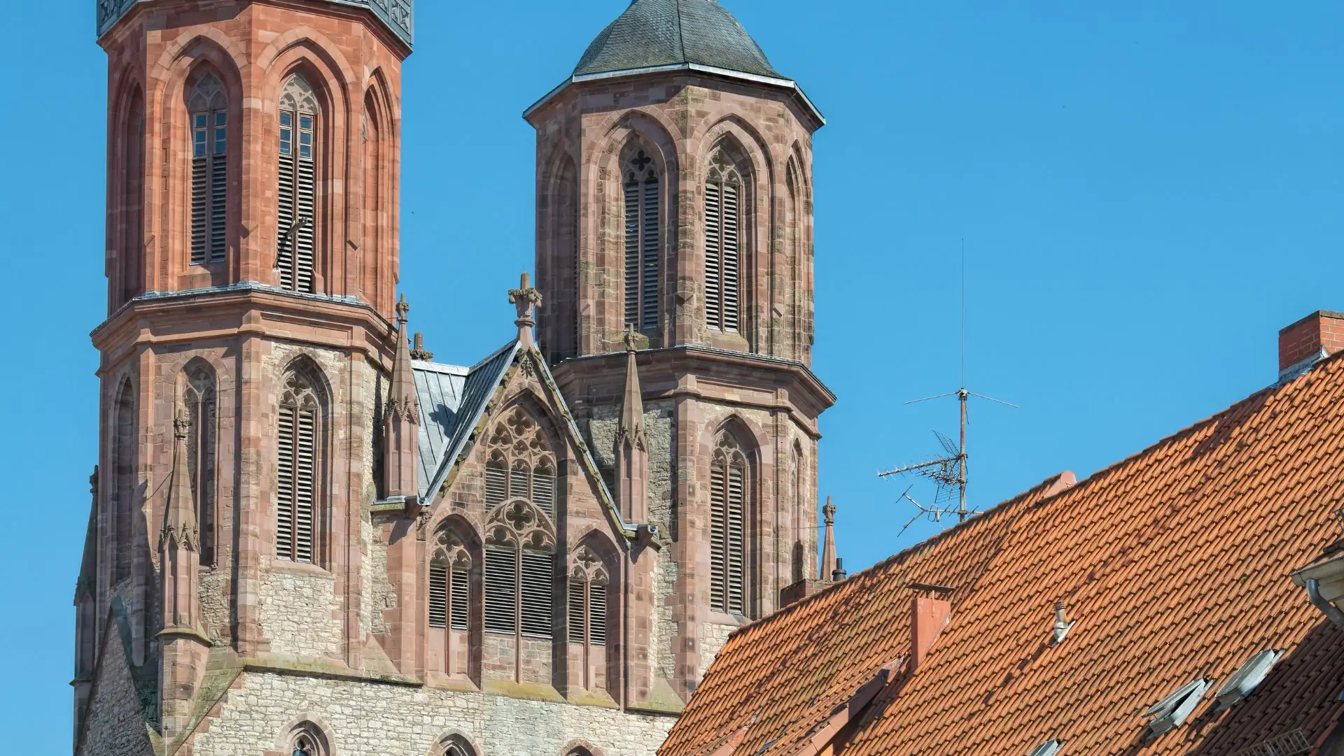 Die Türme der St. Johannis Kirche in Göttingen mit roten Ziegeldächern im Vordergrund
