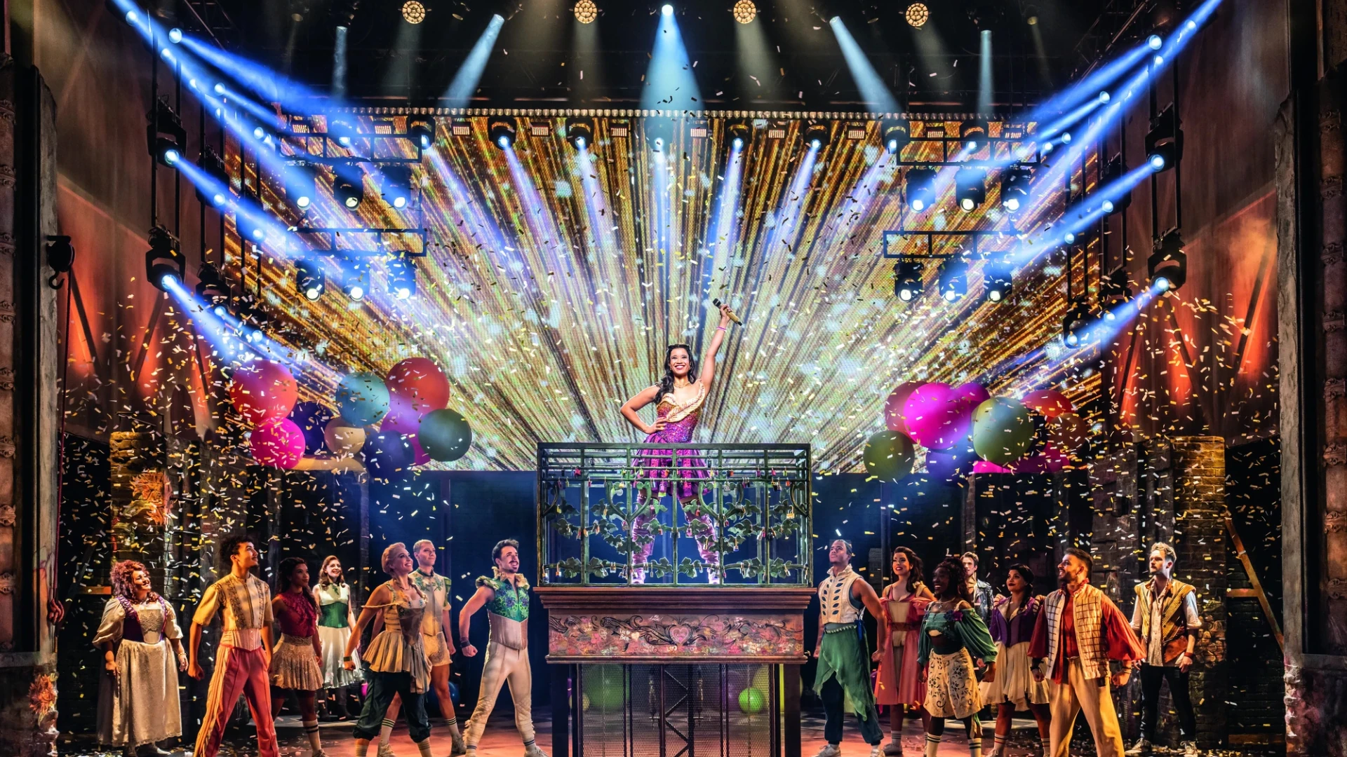 Eine lebhafte Bühnenshow zeigt eine Sängerin auf einem Balkon, umgeben von bunten Luftballons und Konfetti, beleuchtet von dynamischen Bühnenlichtern.
