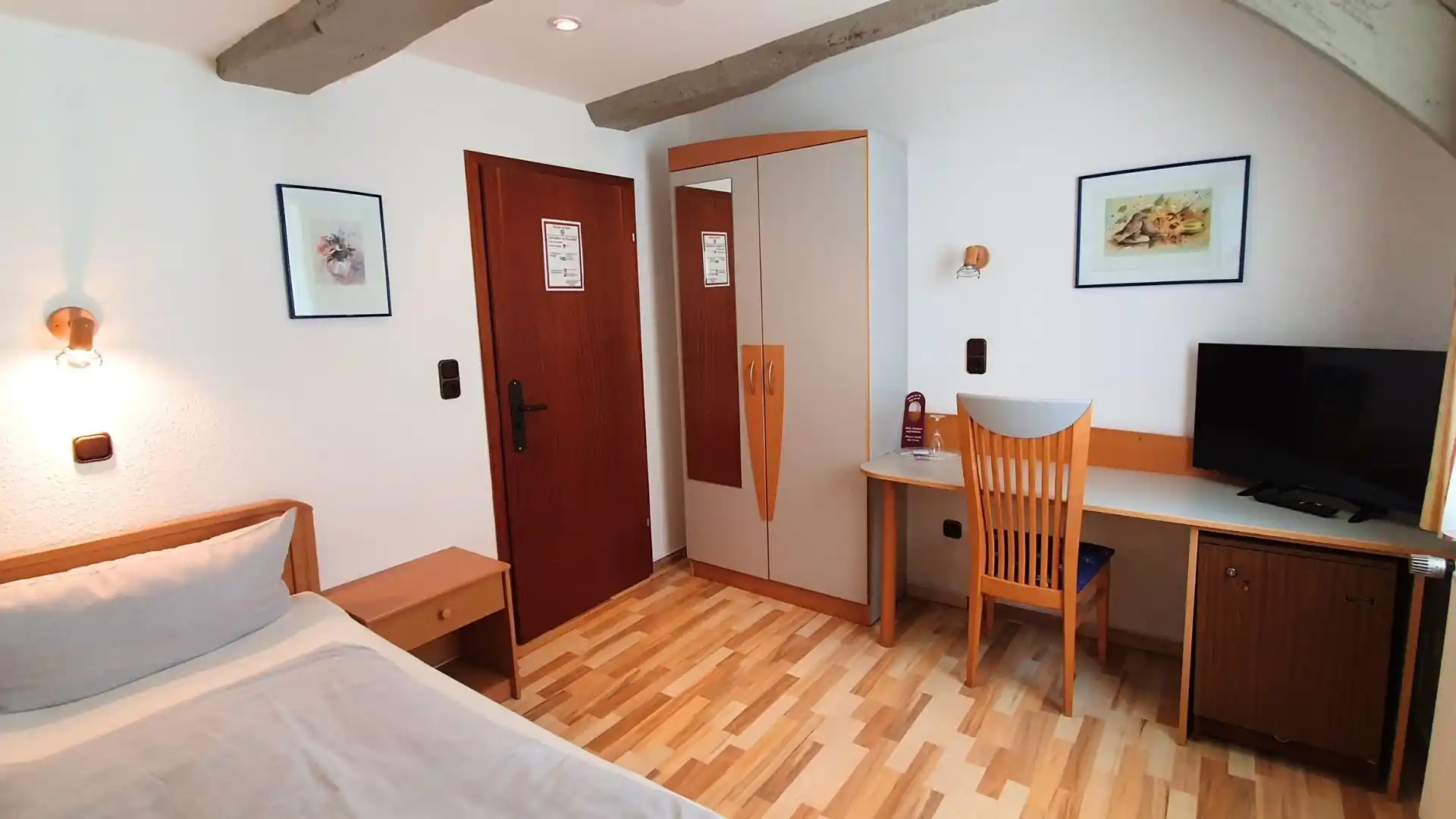 Hotelzimmer mit Bett, Nachttisch, Kleiderschrank, Schreibtisch mit Stuhl und Flachbildfernseher