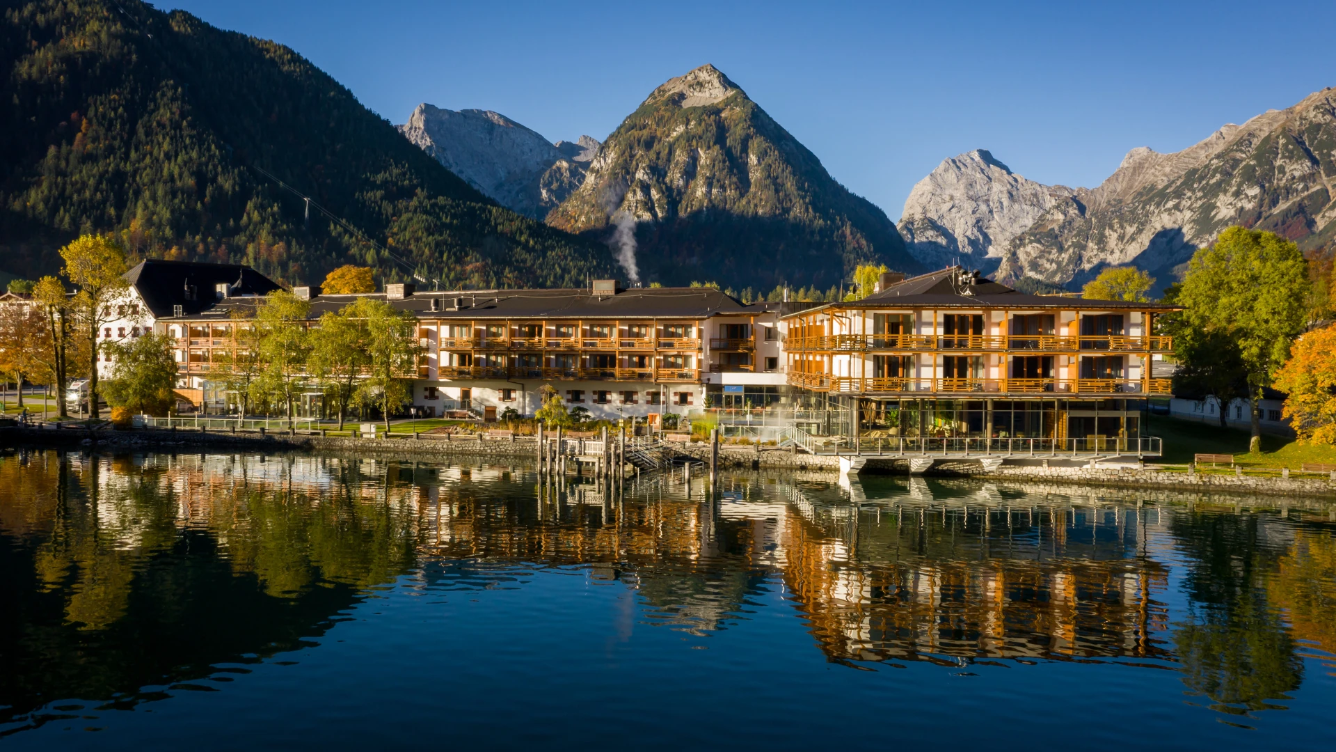 Das aja Fürstenhaus am Achensee präsentiert sich in beeindruckender Kulisse direkt am Ufer des Achensees, eingerahmt von majestätischen Bergen. Die harmonische Architektur und die spiegelnde Wasseroberfläche schaffen eine idyllische Atmosphäre, die Natur und Komfort vereint.