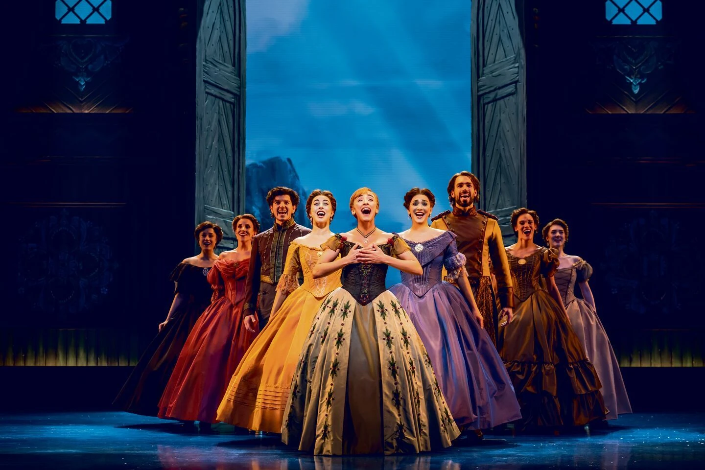 Disney Die EIskönigin Szenenbild; Frauen und Männer in majestätischen Klamotten in einer Reihe und singen