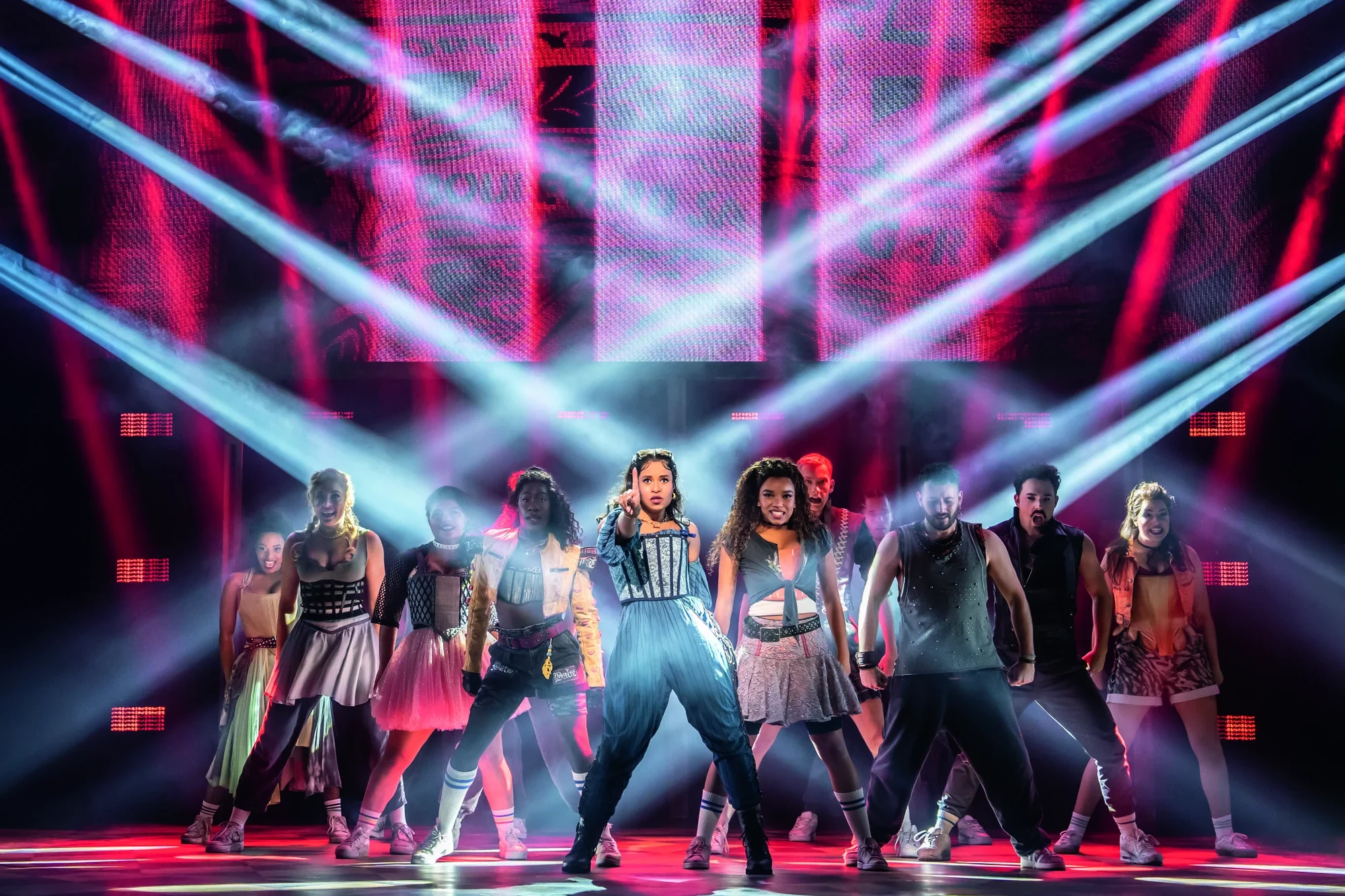 Eine lebhafte Tanzvorführung mit einer Gruppe von Tänzern in dynamischen Posen, beleuchtet von bunten Bühnenlichtern und einer lebendigen Kulisse.