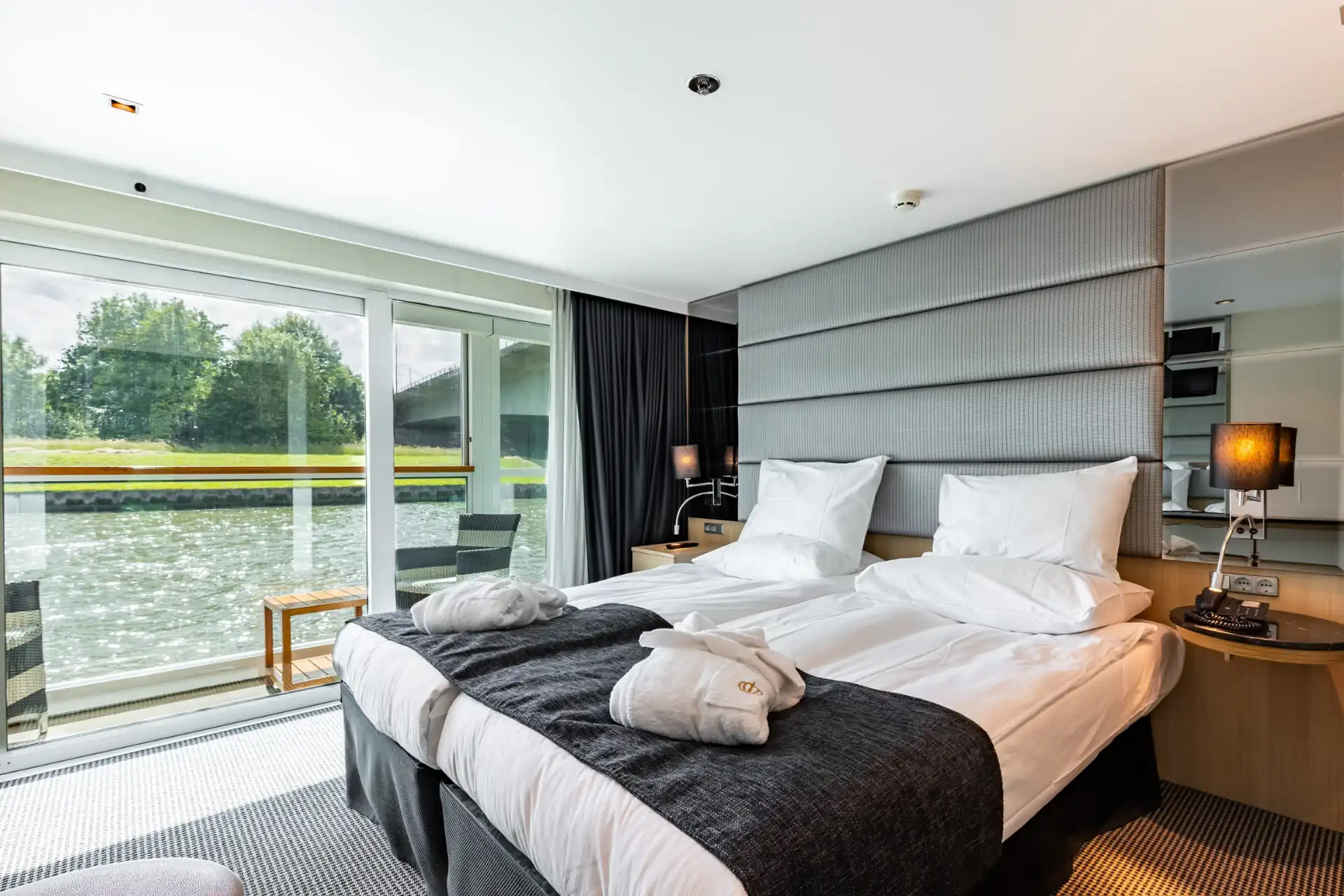 Geräumige Doppelkabine auf dem Mittel- und Oberdeck des Flusskreuzfahrtschiffs KD Moment mit modernen Möbeln, einem großen Bett und Panoramafenstern für einen herrlichen Ausblick.