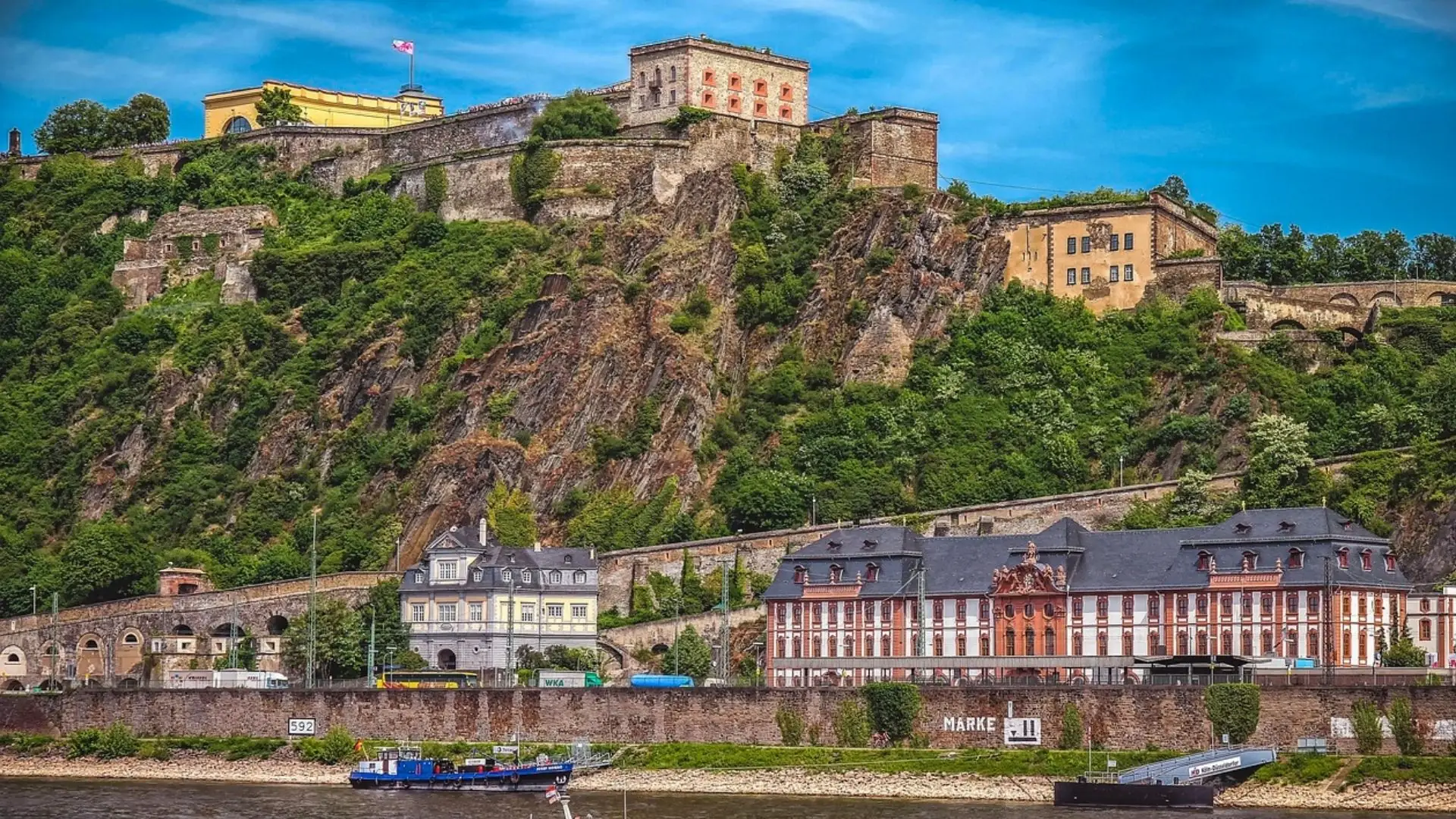 Festung Ehrenbreitstein auf einem steilen Felsen über dem Rhein in Koblenz, mit historischen Gebäuden und grüner Vegetation