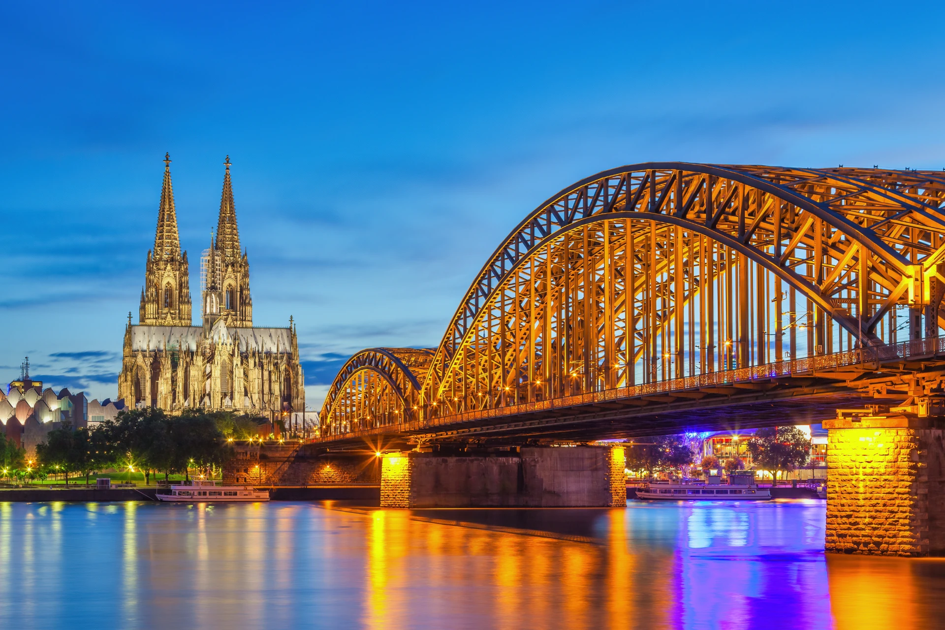 Blick auf den Kölner Dom und die Hohenzollernbrücke bei Abenddämmerung.