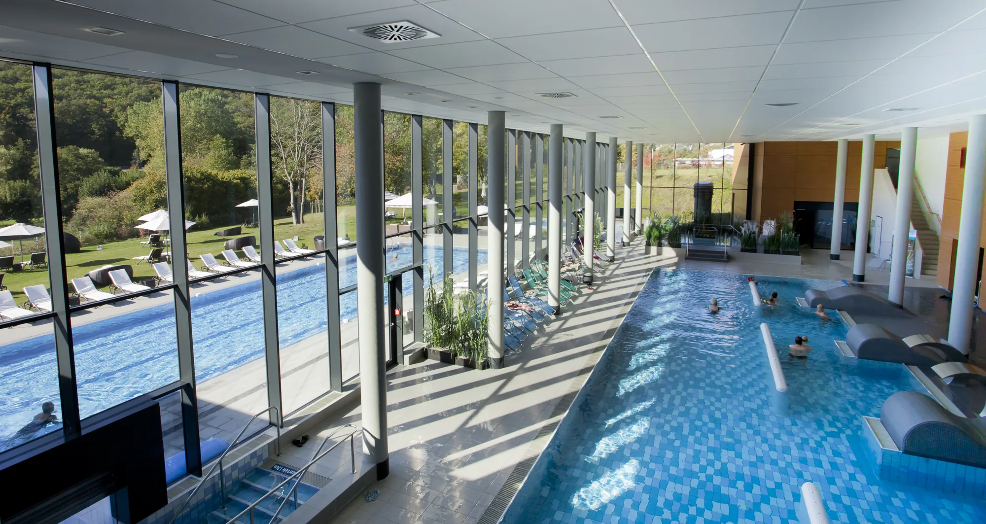 Der Innenpool und das Außenbecken und Liegestühle von oben fotografiert