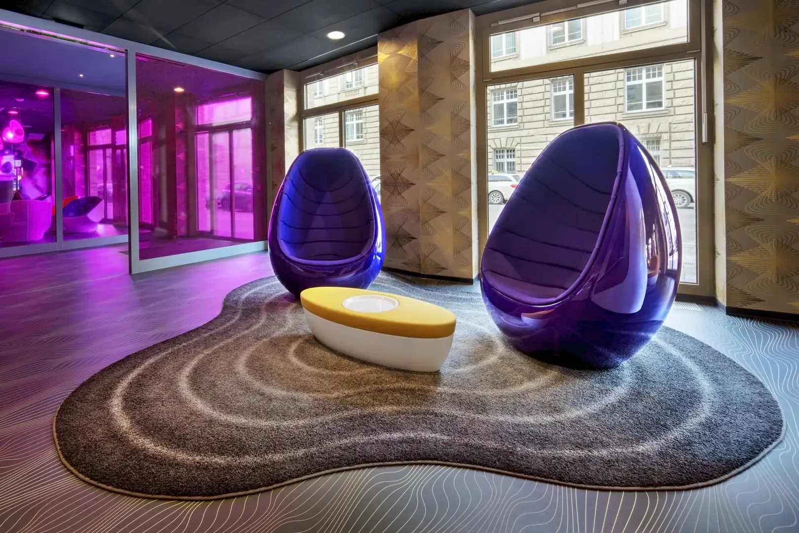 Stilvolle moderne Sitzmöbel in einer Lounge mit lila und gelben Akzenten.