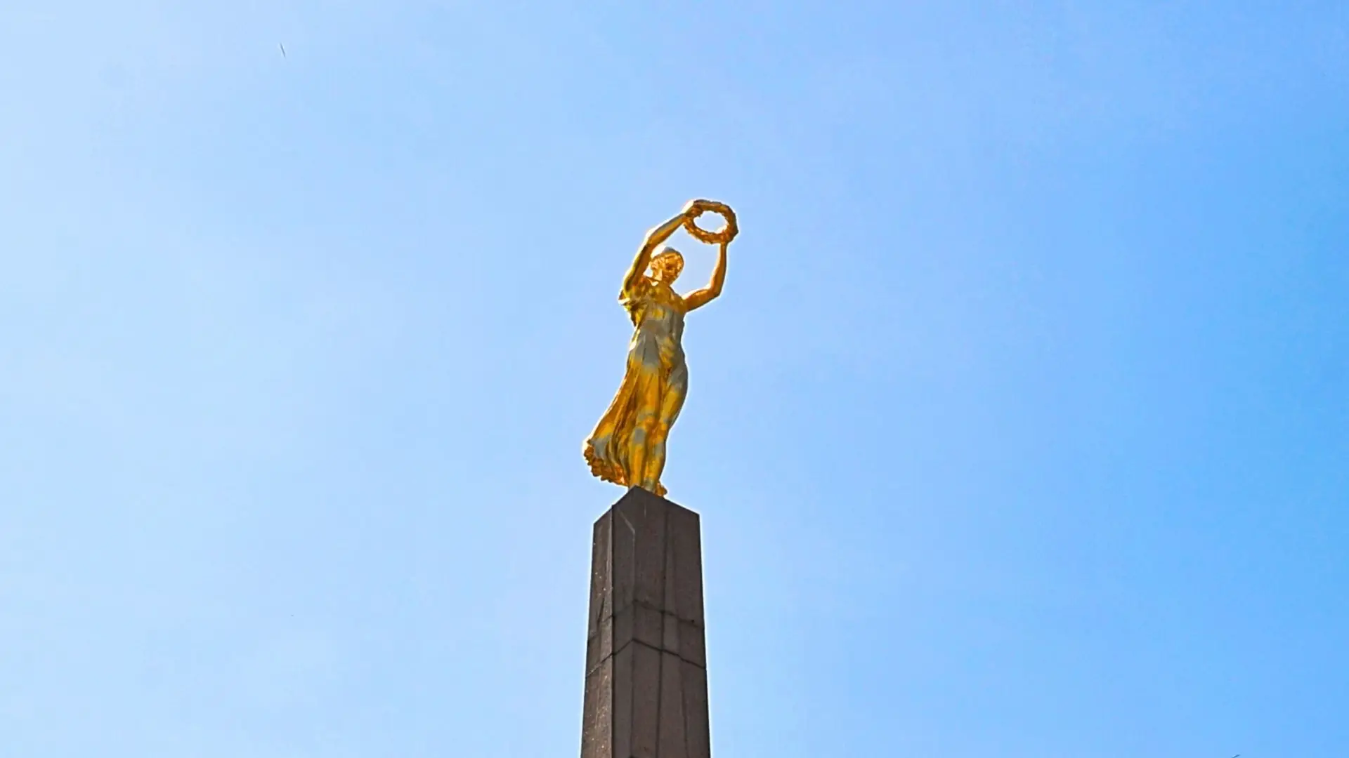 Eine goldene Statue auf einer Säule gegen den blauen Himmel.