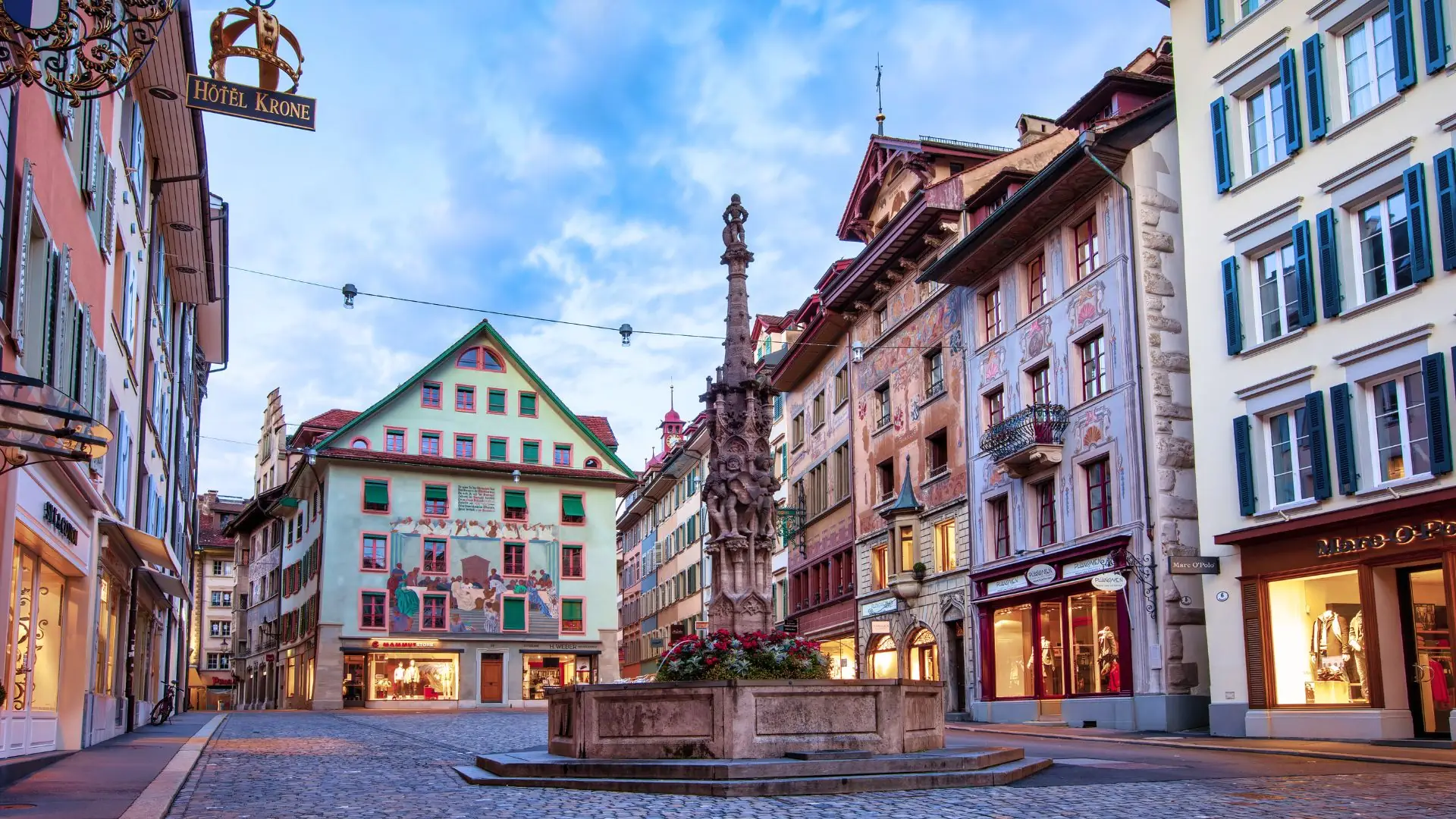 Brunnen im Stadtzentrum von Luzern, umgeben von traditioneller Architektur.