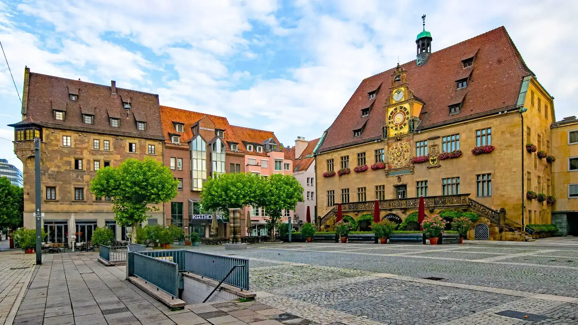 Das Alte Rathaus am Marktplatz in Heilbronn mit Fachwerkfassade, Uhrturm und umliegenden historischen Gebäuden bei blauem Himmel mit Wolken
