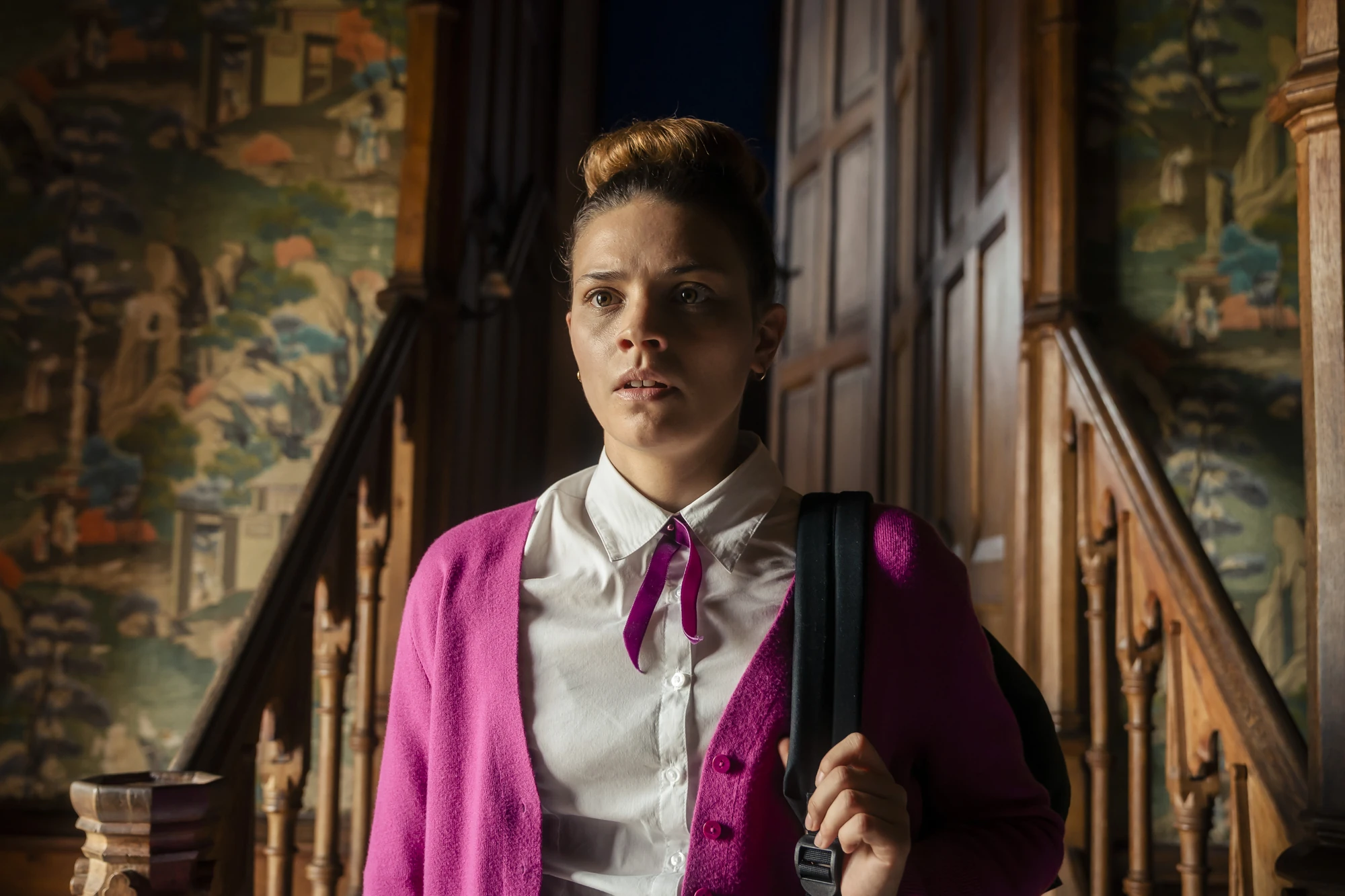 Maxton Hall Szenenbild - Ruby entdeckt auf einer Treppe des Schlosses etwas Unerwartetes. Ihr Blick verrät Überraschung und Sorge, während sie in ihrer Schuluniform verharrt.