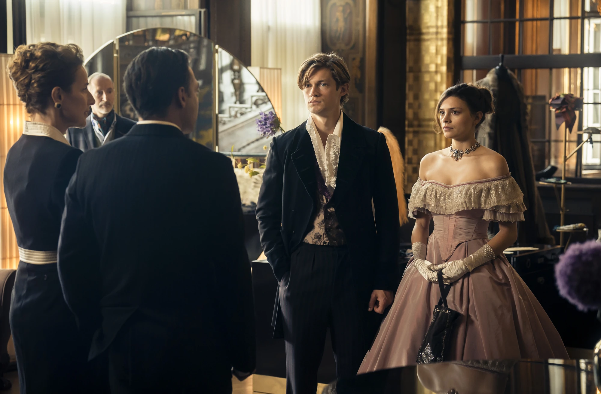 Maxton Hall Szenenbild - Gegenüber von James Beaufort und Ruby Bell sind 2 Erwachsene. Die Stimmung ist etwas angespannt. Alle sind schick gekleidet.