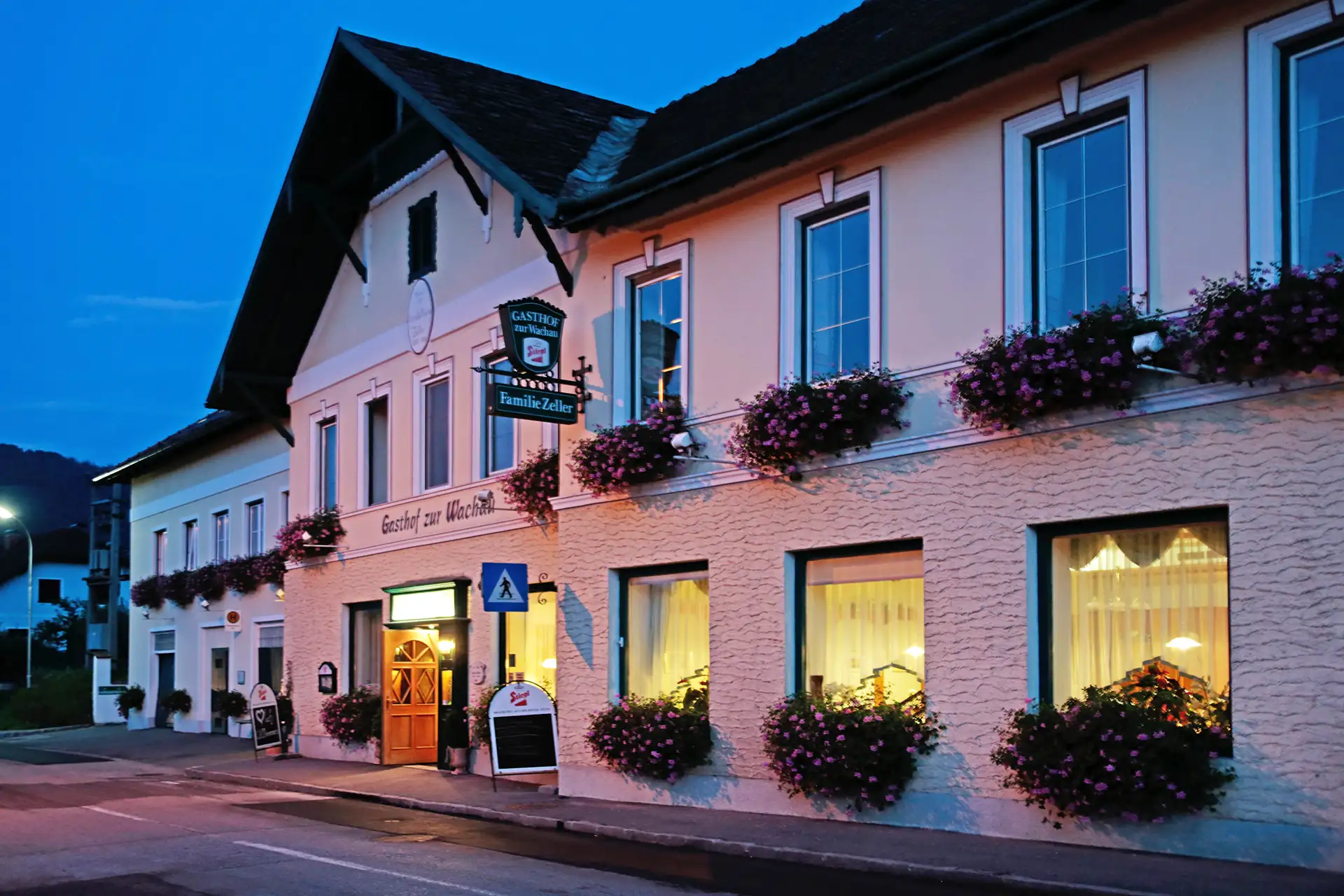 Außenansicht vom Gasthof zur Wachau am Abend mit Licht in den unteren Fenstern und üppigen Blumenkästen, ein Beispielhotel für die Radreise Passau-Wien