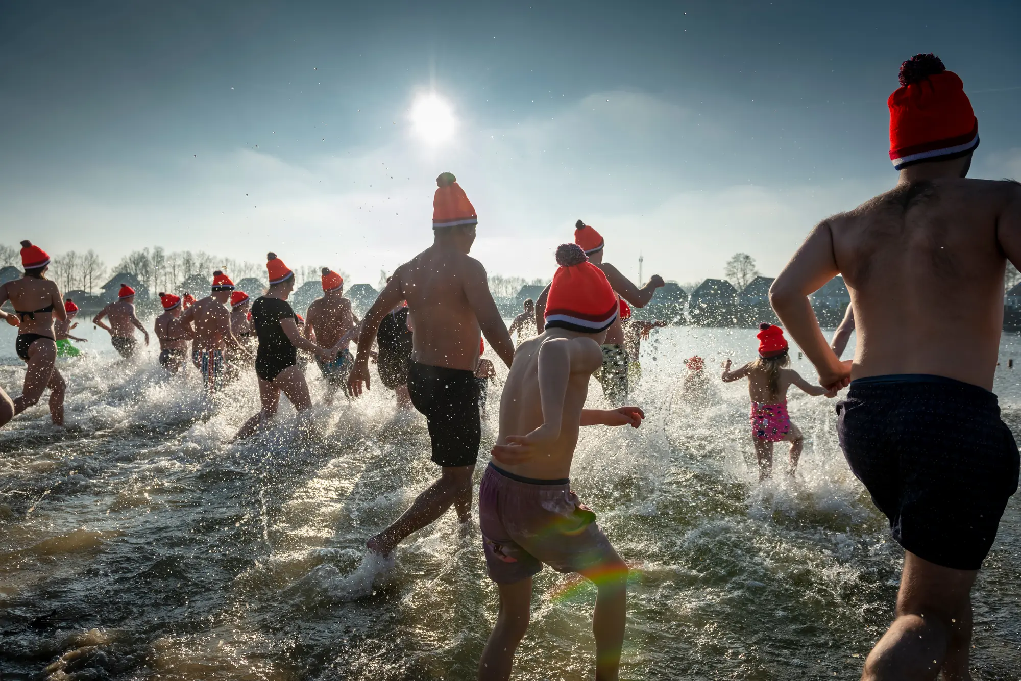 Traditionelles Neujahrsschwimmen am Strand von Scheveningen in Den Haag. Mutige stürzen sich mit roten Wollmützen ins eiskalte Wasser.