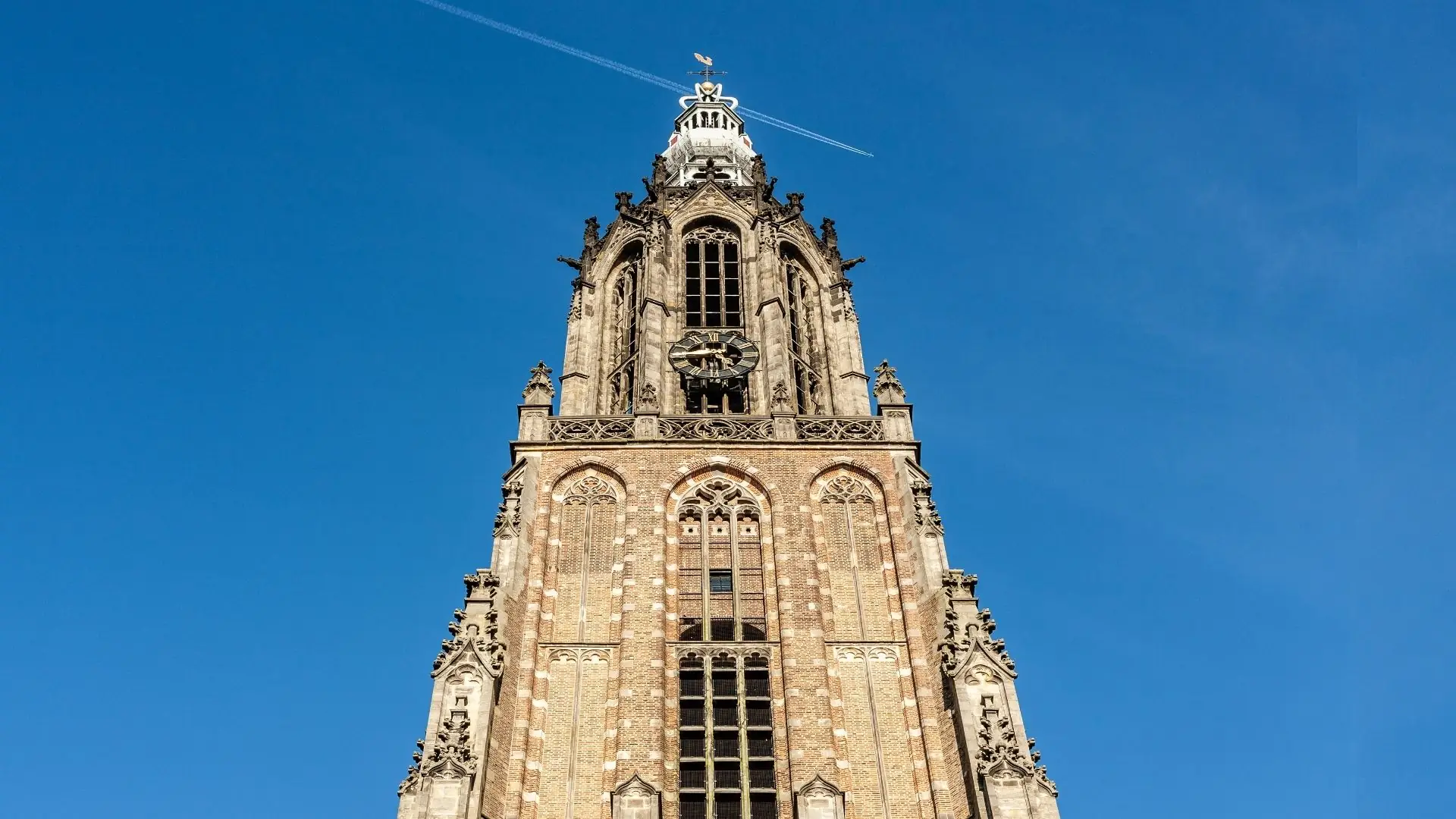 Blick auf den Onze-Lieve-Vrouwetoren in Amersfoort mit gotischem Turm und klar blauem Himmel im Hintergrund.