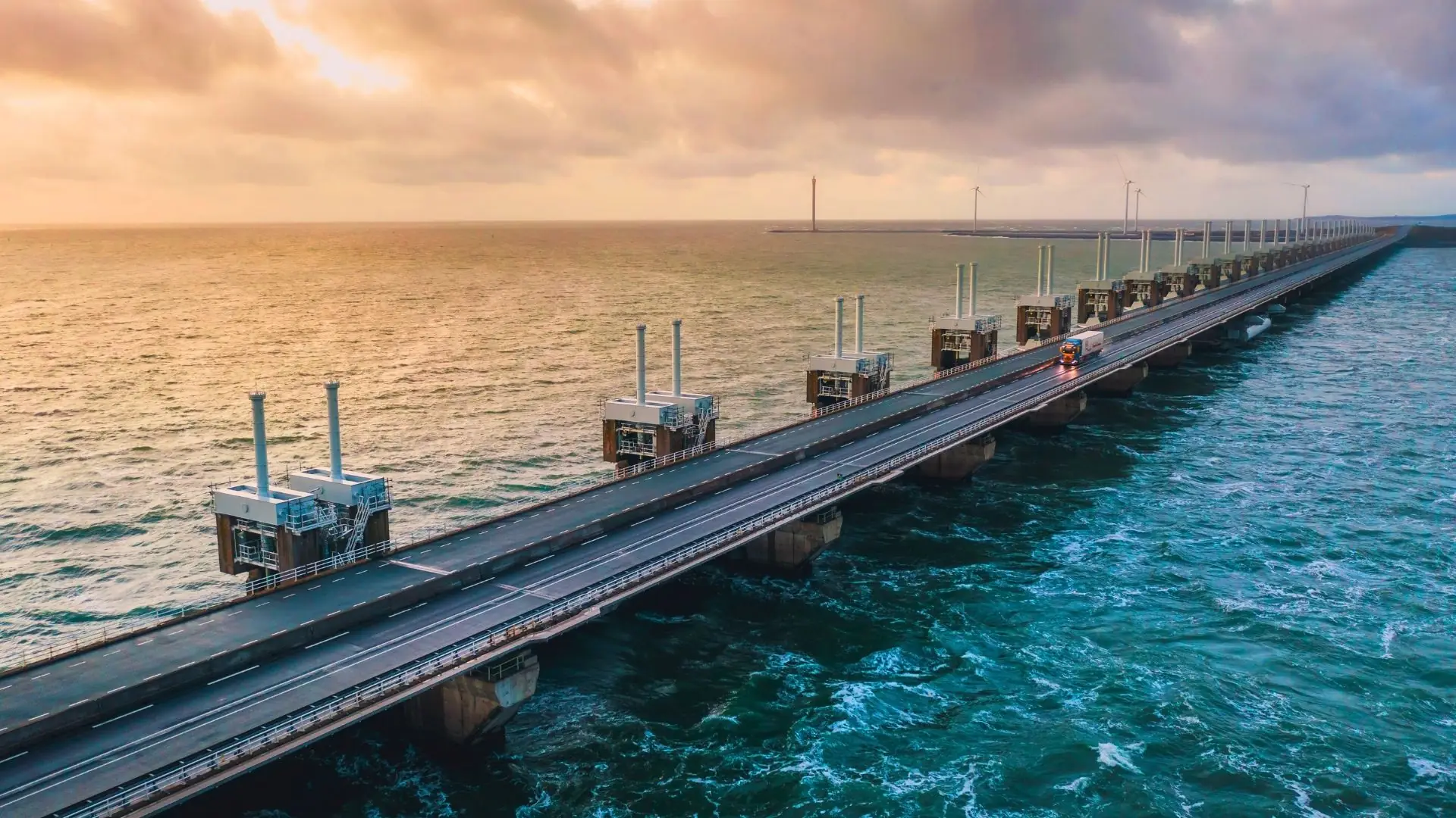 Luftaufnahme der Oosterscheldekering in Zeeland bei Sonnenuntergang mit langen Dammkonstruktionen und ruhigem Meer.