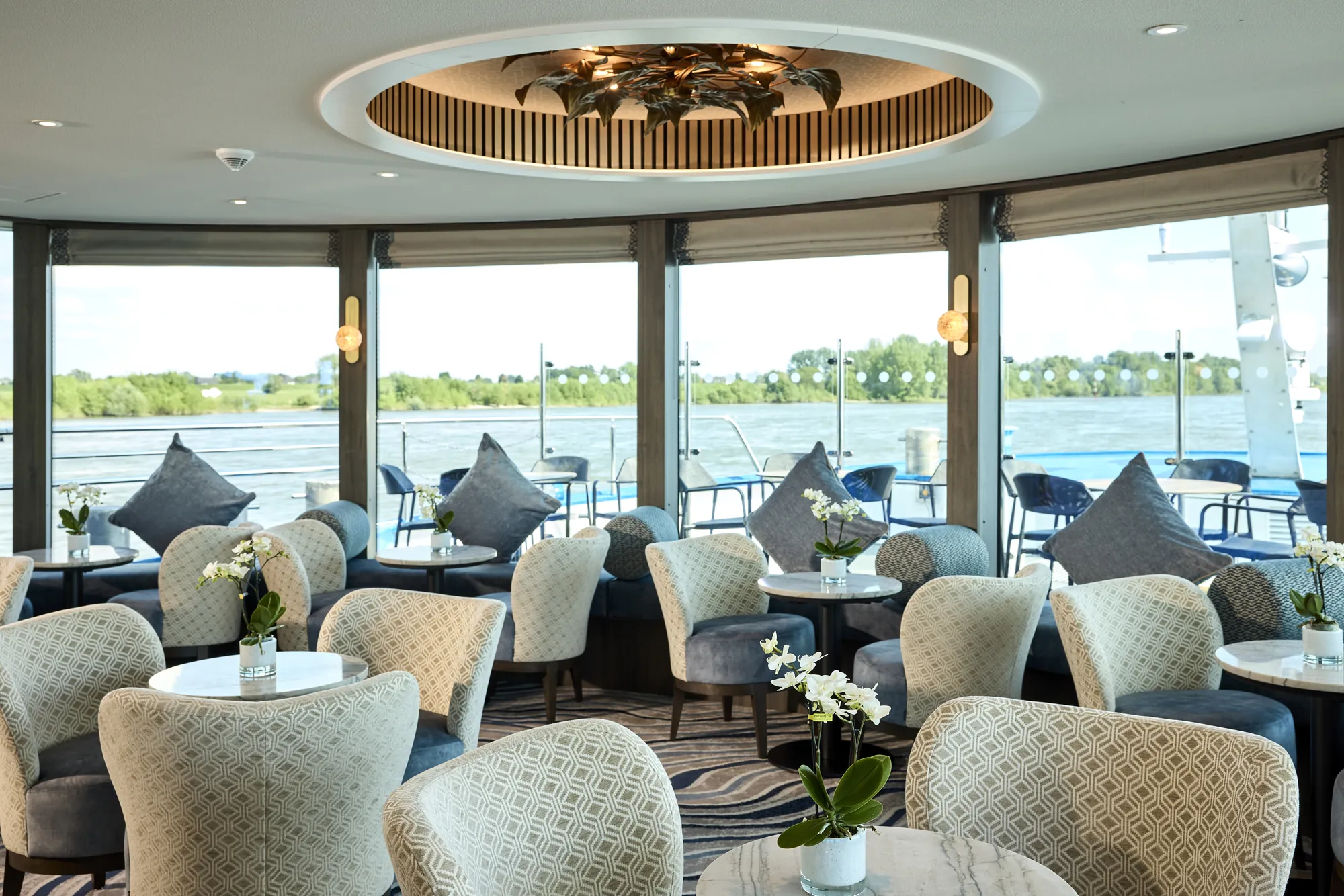 Lounge-Bereich auf einem Kreuzfahrtschiff mit modernen Möbeln und Aussicht.