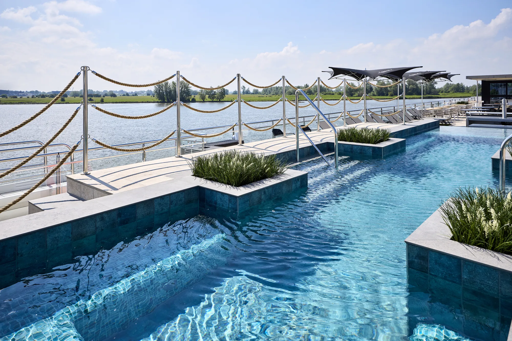 Luxuriöser Pool mit Blick auf das Wasser und moderne Liegen