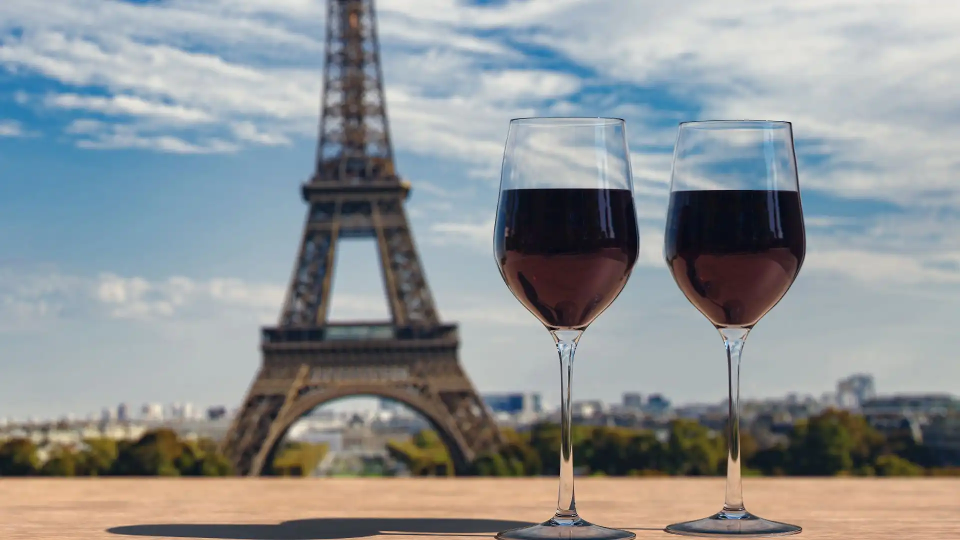 Zwei Gläser Wein vor dem Hintergrund des Eiffelturms und der Pariser Skyline.