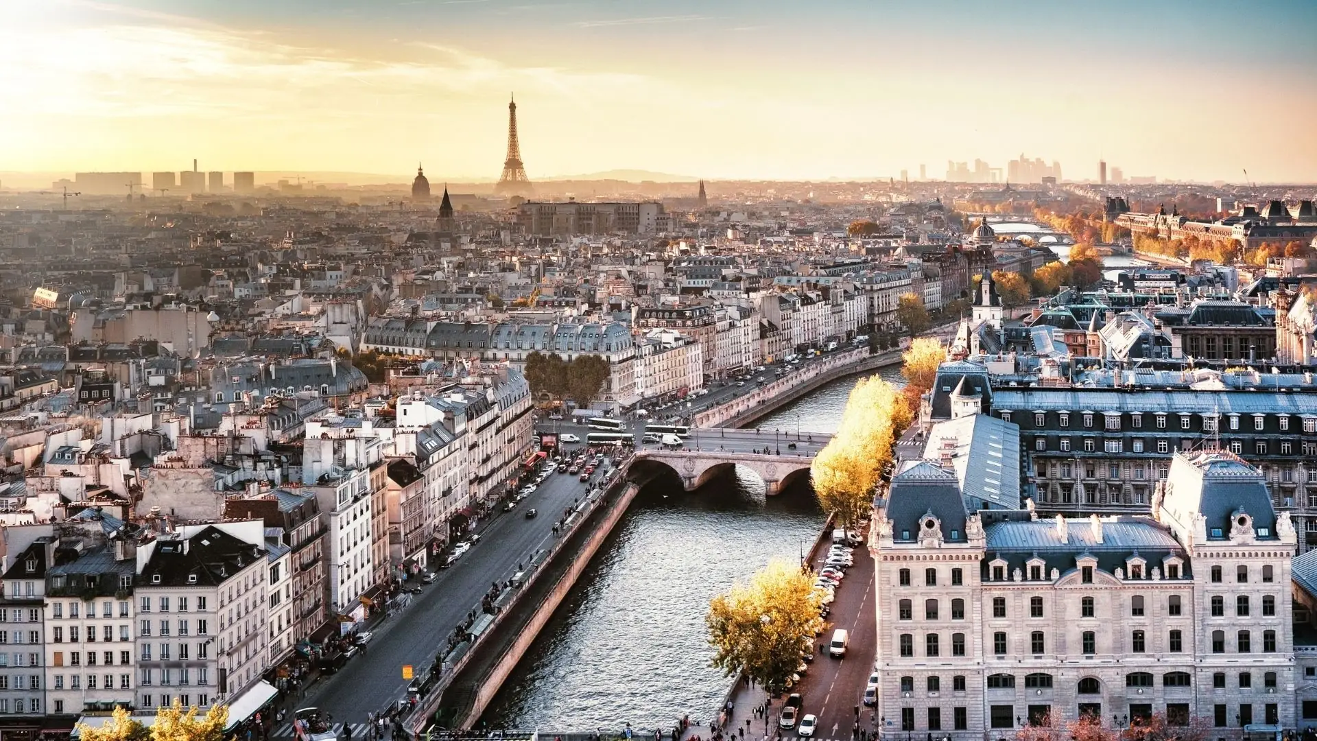 Blick über die Seine mit mehreren Brücken und Gebäuden, im Hintergrund der Eiffelturm bei Sonnenuntergang.