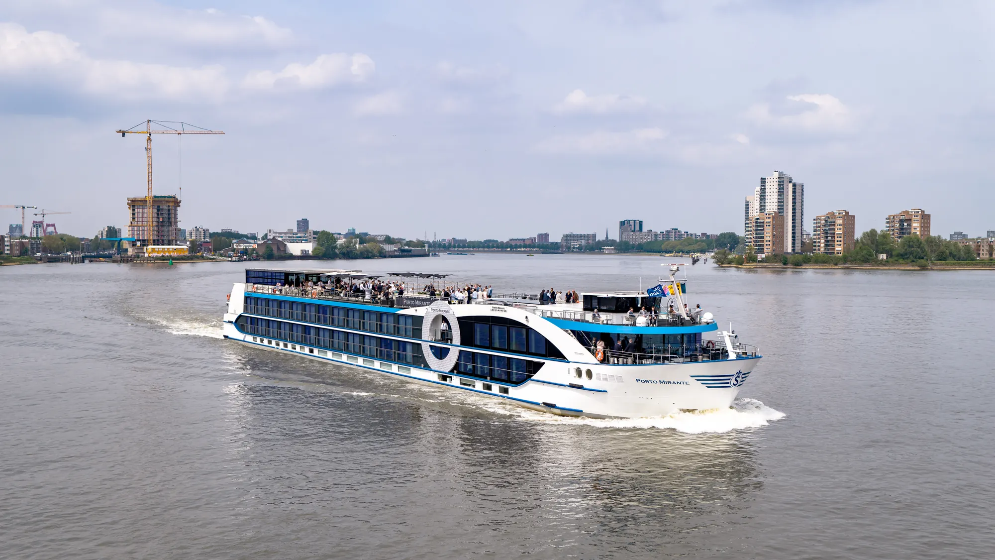 Ein modernes Flusskreuzfahrtschiff auf dem Wasser mit Passagieren an Bord.