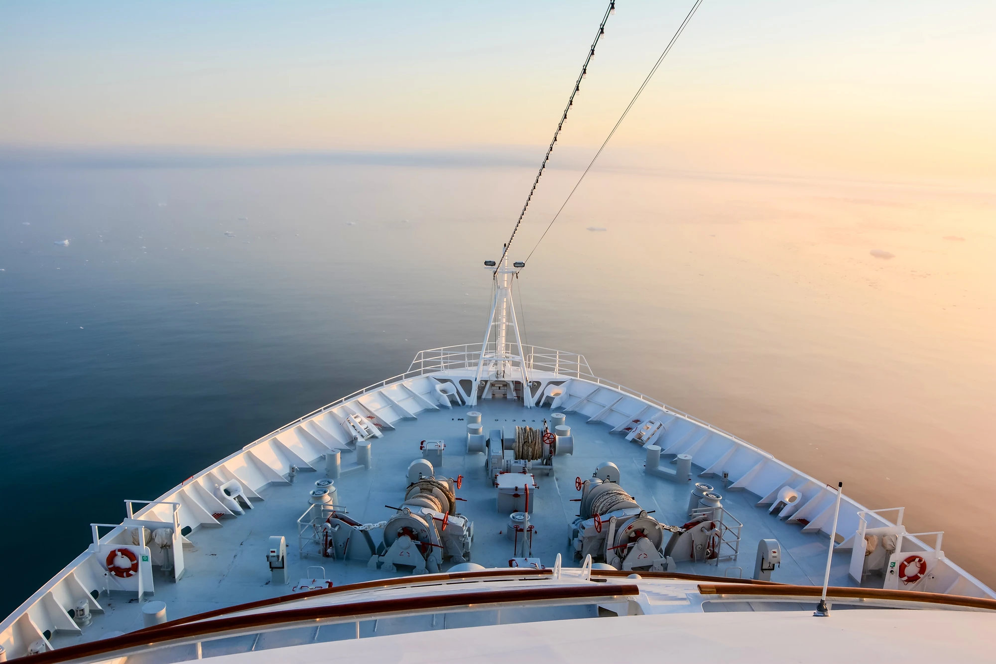 Blick von der Vorderseite eines Schiffes auf ruhiges Wasser bei Sonnenaufgang.