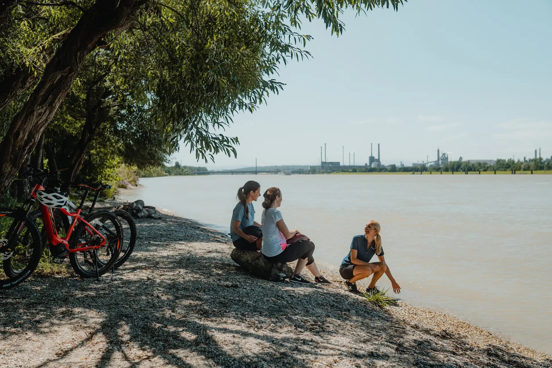 Radfahrerinnen sitzen am Ufer der Donau - Linzer Riviera