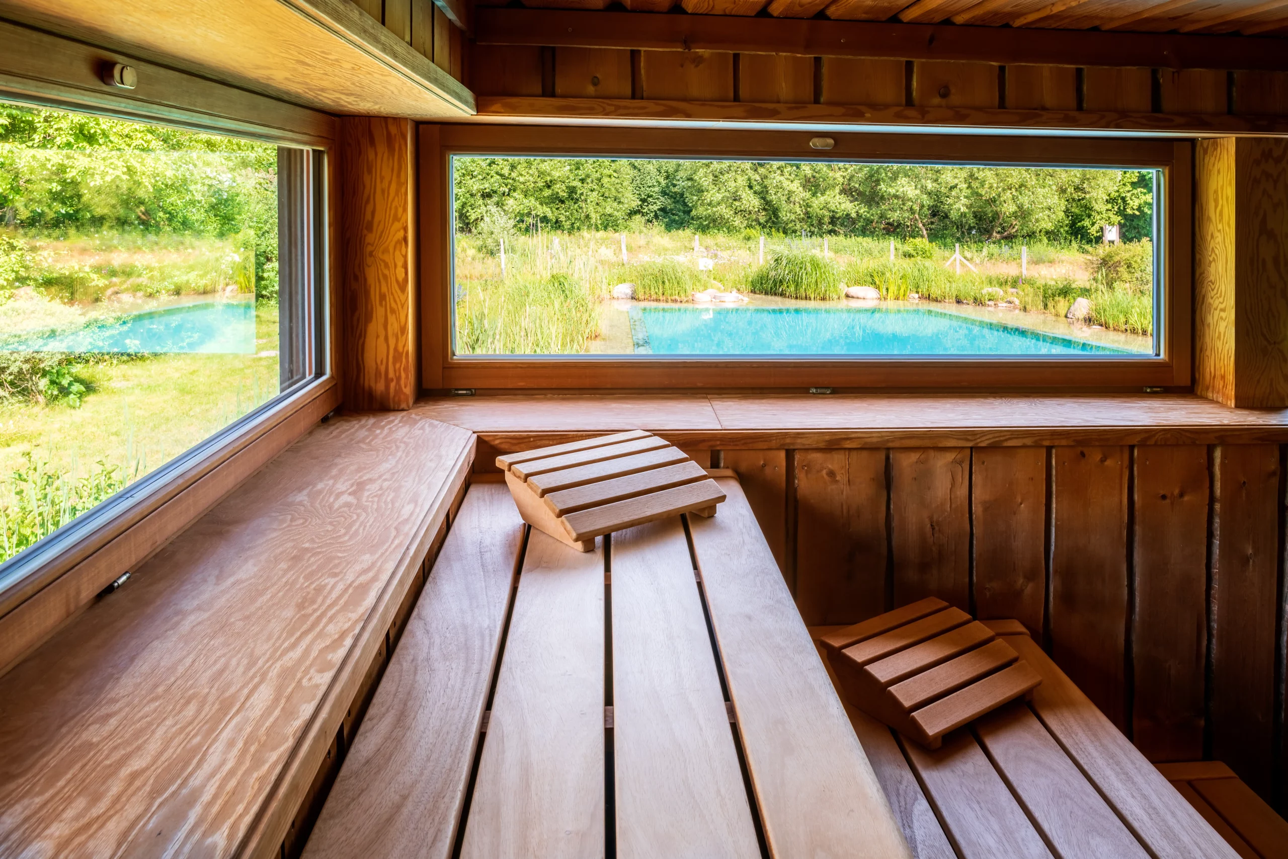 Holzsauna mit Blick auf den Garten und den blauen Pool.