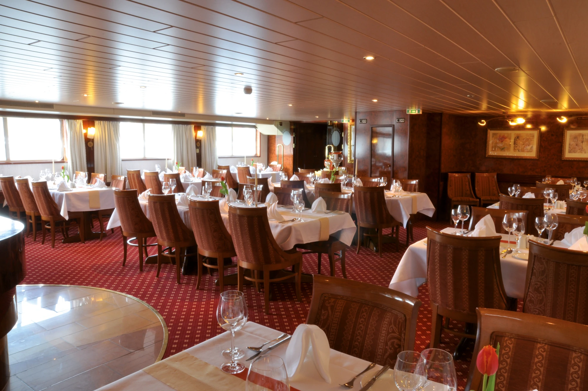 Beleuchtetes Restaurant auf der MS SANS SOUCI mit gedeckten Tischen und Pflanzen