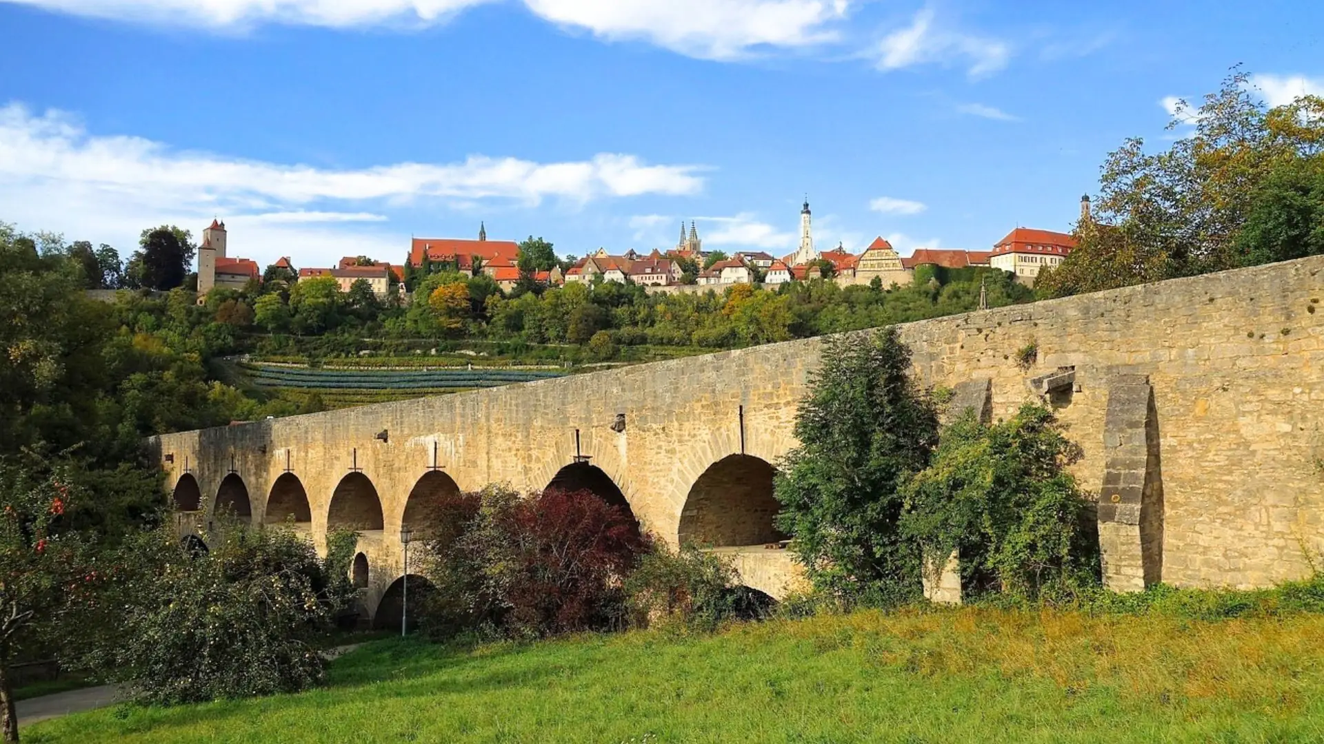 Steinerne Brücke mit mehreren Bögen vor der historischen Altstadt von Rothenburg ob der Tauber.