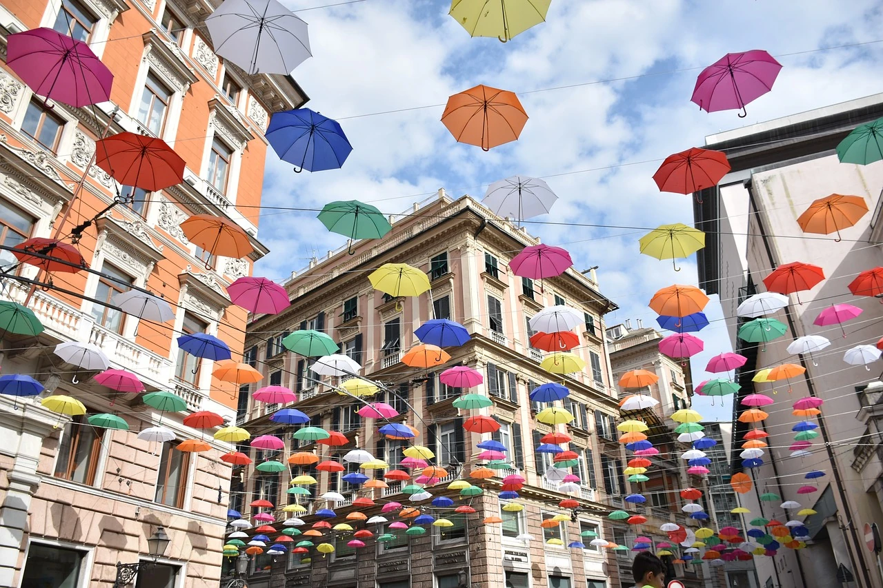 Ein Netzt aus Schirmen in vielen bunten Farben überspannt eine Fußgängerzone in Italien